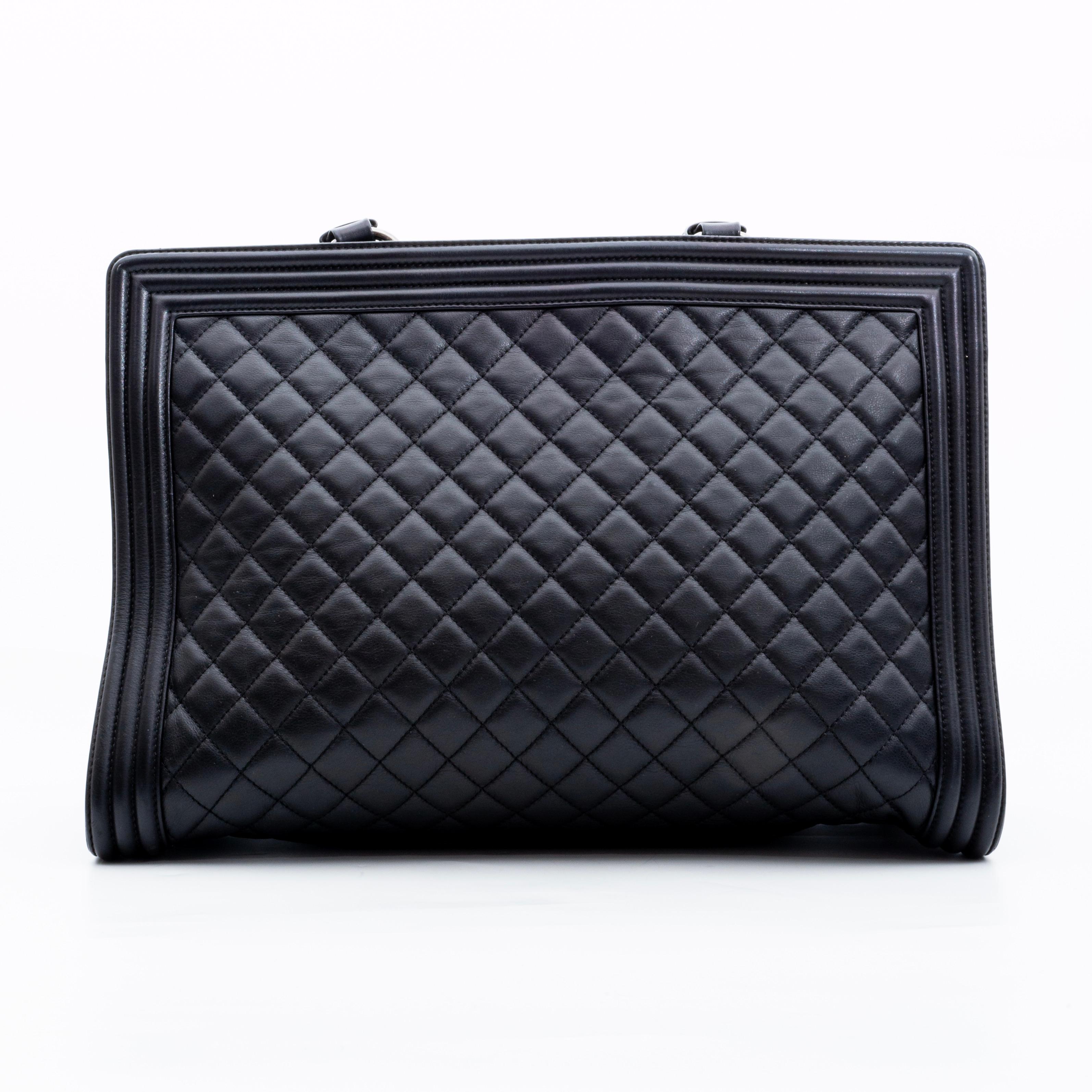 This bag is made with soft and supple lambskin leather in black with diamond quilting in black. The bag features dual flat top handles attached by metal links, aged Ruthenium hardware, Chanel 