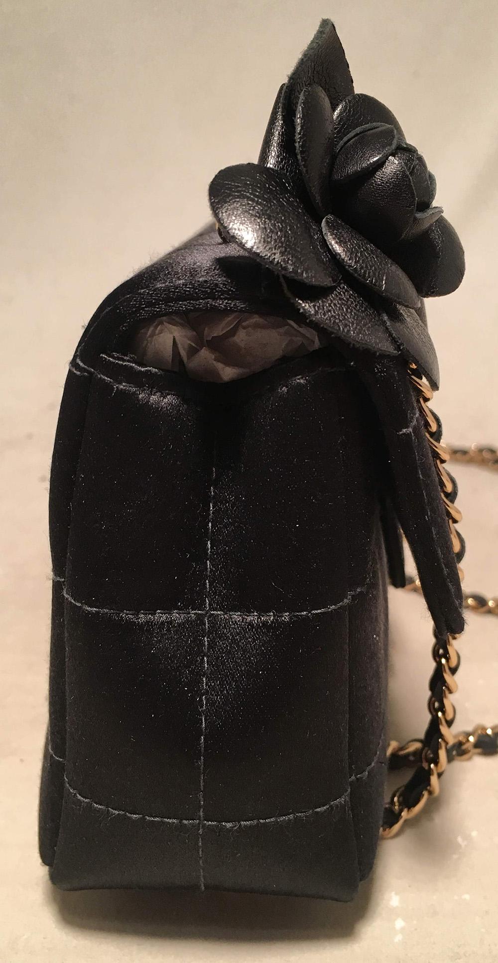 Chanel Quilted Black Silk Mini Camellia Classic Flap Shoulder Bag in excellent condition. Square quilted black silk exterior trimmed with matte gold hardware and an adorable black leather camellia flower along the top right side at one end of the