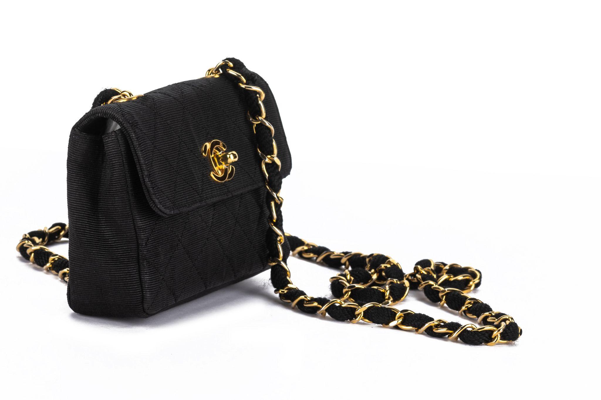 This Chanel black mini flap bag with gold hardware and diamond canvas quilting, fabric and chain-link shoulder strap, and a signature interlocking CC turn-lock fastening is a  classic piece from collection 1. Comes with an original dust