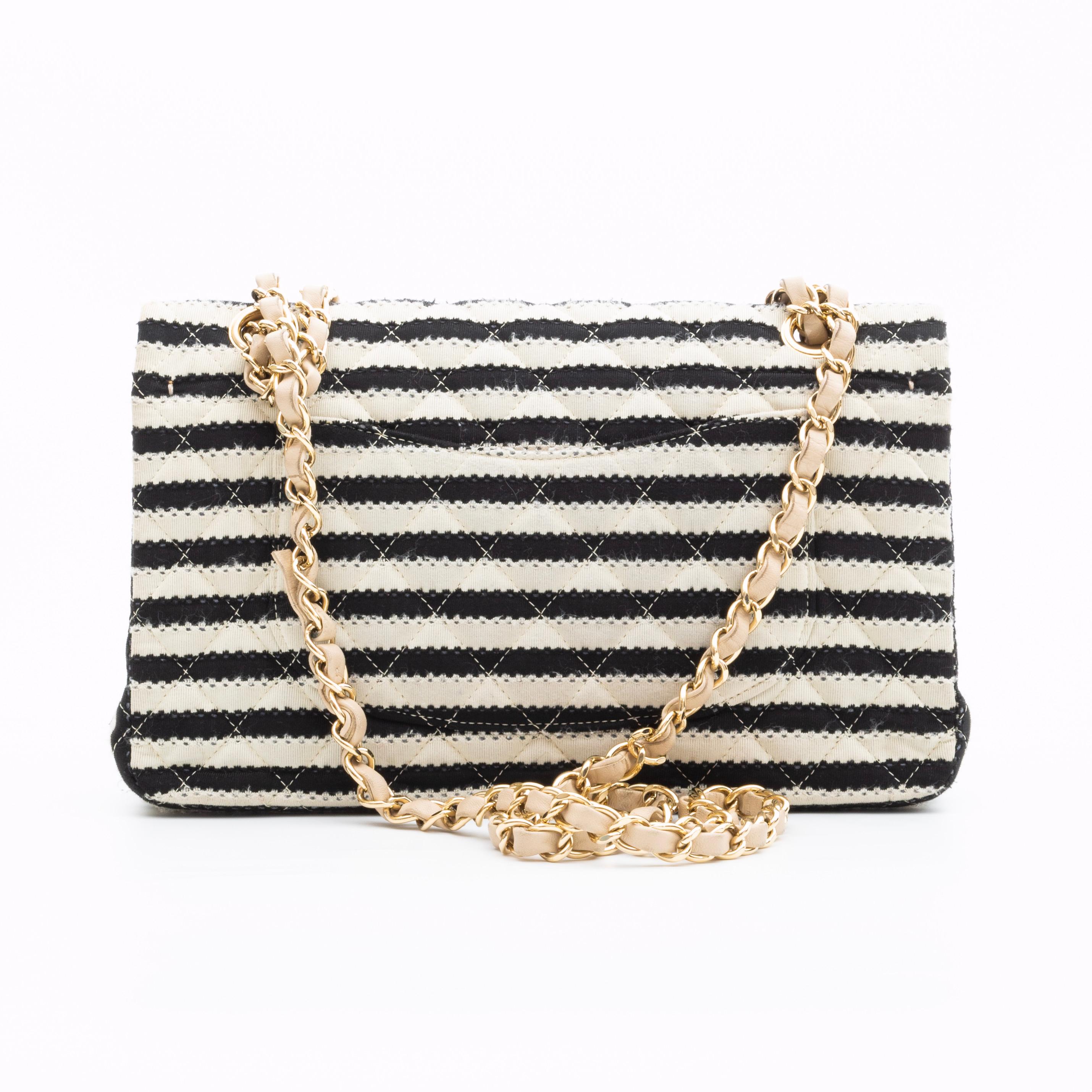This limited edition Chanel Coco Sailor double flap bag is made with textured black and white striped cotton knit fabric and features an adjustable light gold chain interlaced with leather shoulder strap and CC turnlock closure. The top opens to a