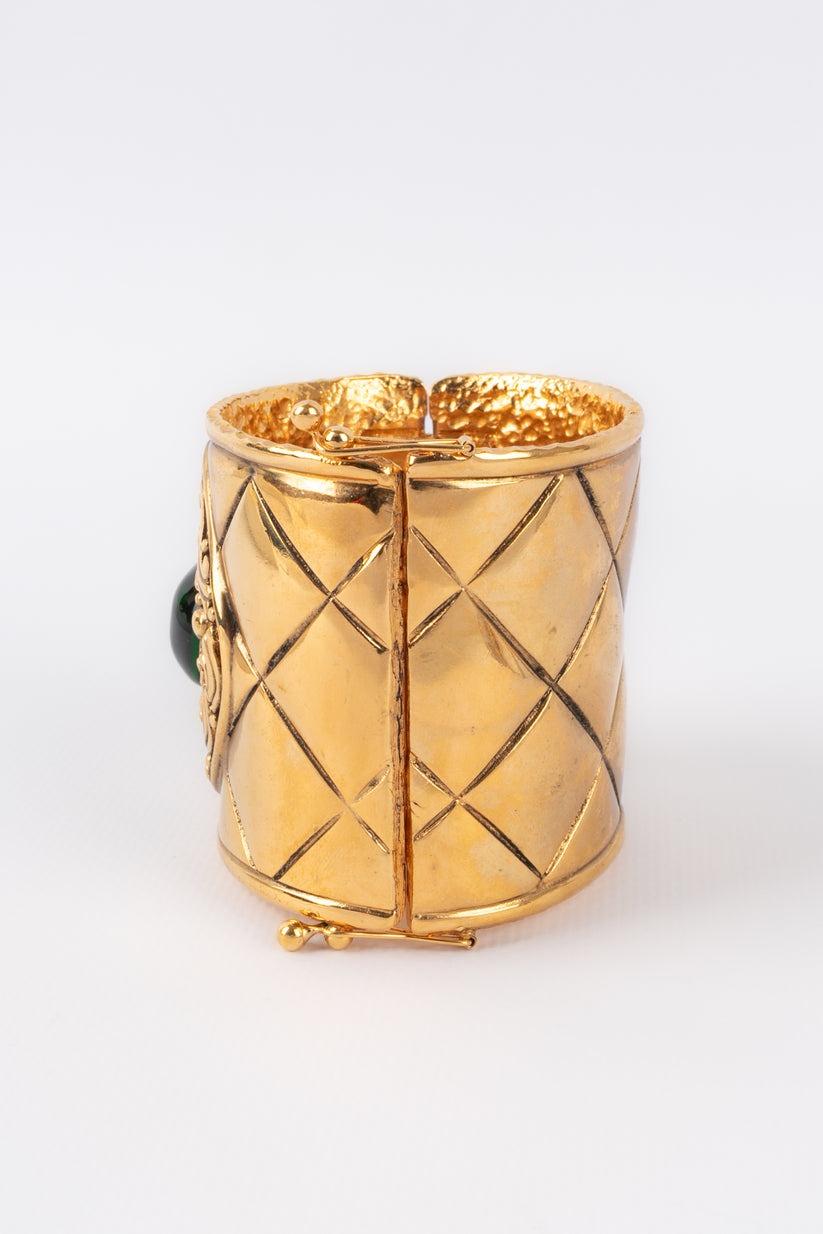 Chanel - (Made in France) Quilted golden metal cuff bracelet ornamented with a green glass paste cabochon. Jewelry engraved with the S of Sales.

Additional information:
Condition: Good condition
Dimensions: Wrist circumference: 17 cm - Opening: 4
