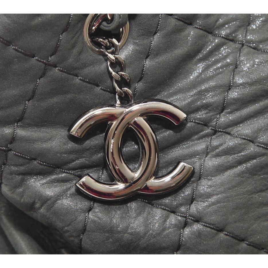 GUARANTEED AUTHENTIC CHANEL LARGE JUST MADEMOISELLE BOWLING BAG

Design: 
- Black iridescent quilted leather.
- Dual chain shoulder straps.
- Shiny gunmetal metal CC charm and hardware.
- Top snap closure.
- 4 metal bottom feet.
- Interior lined in