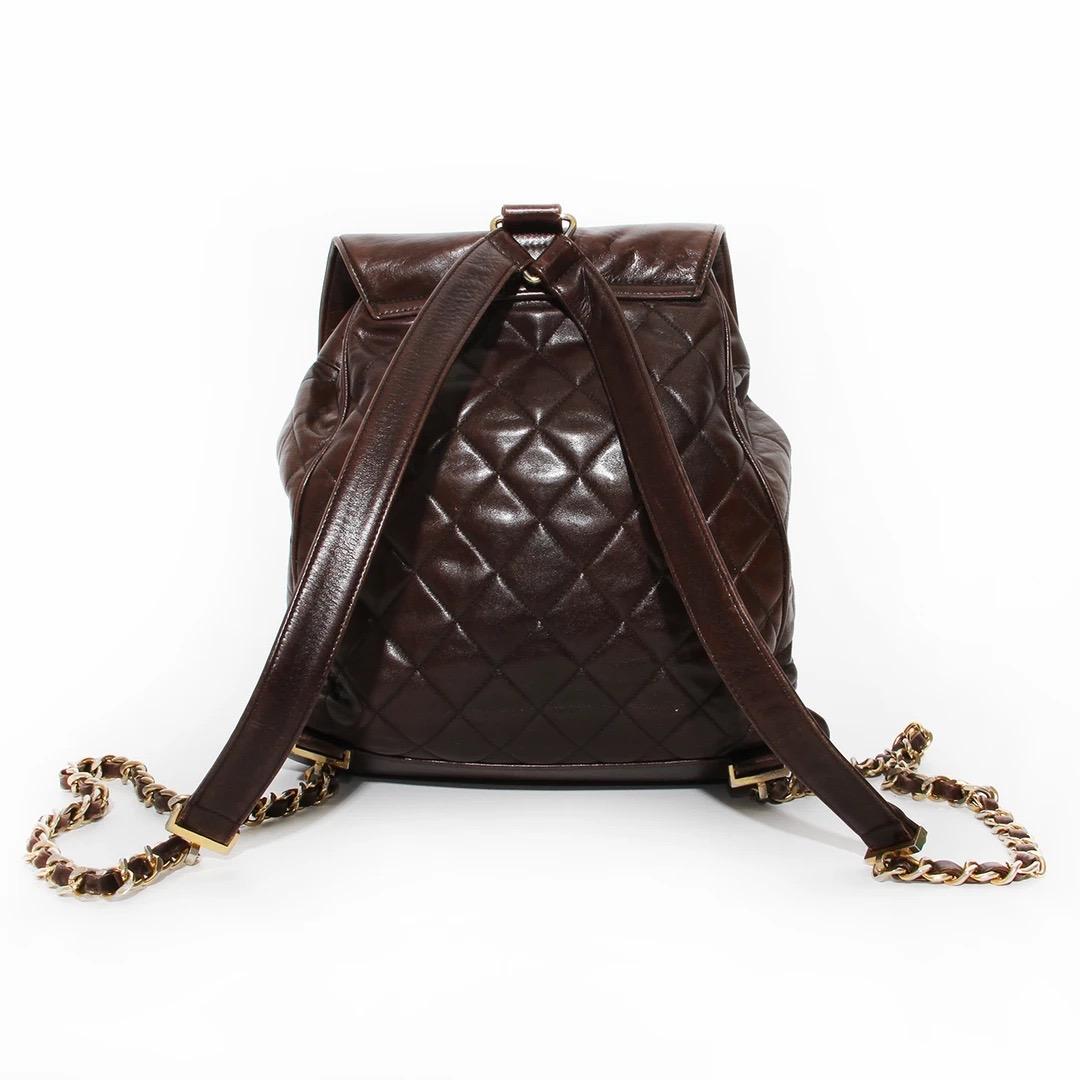 Chanel Backpack 
Vintage 
Circa 1990's
Brown Lambskin 
Quilted leather detail 
Front flap with interlocked CC turn lock 
Drawstring closure at top 
Gold 
Backpack style straps 
Triangular gold hardware for straps
Gold chain with leather detail on