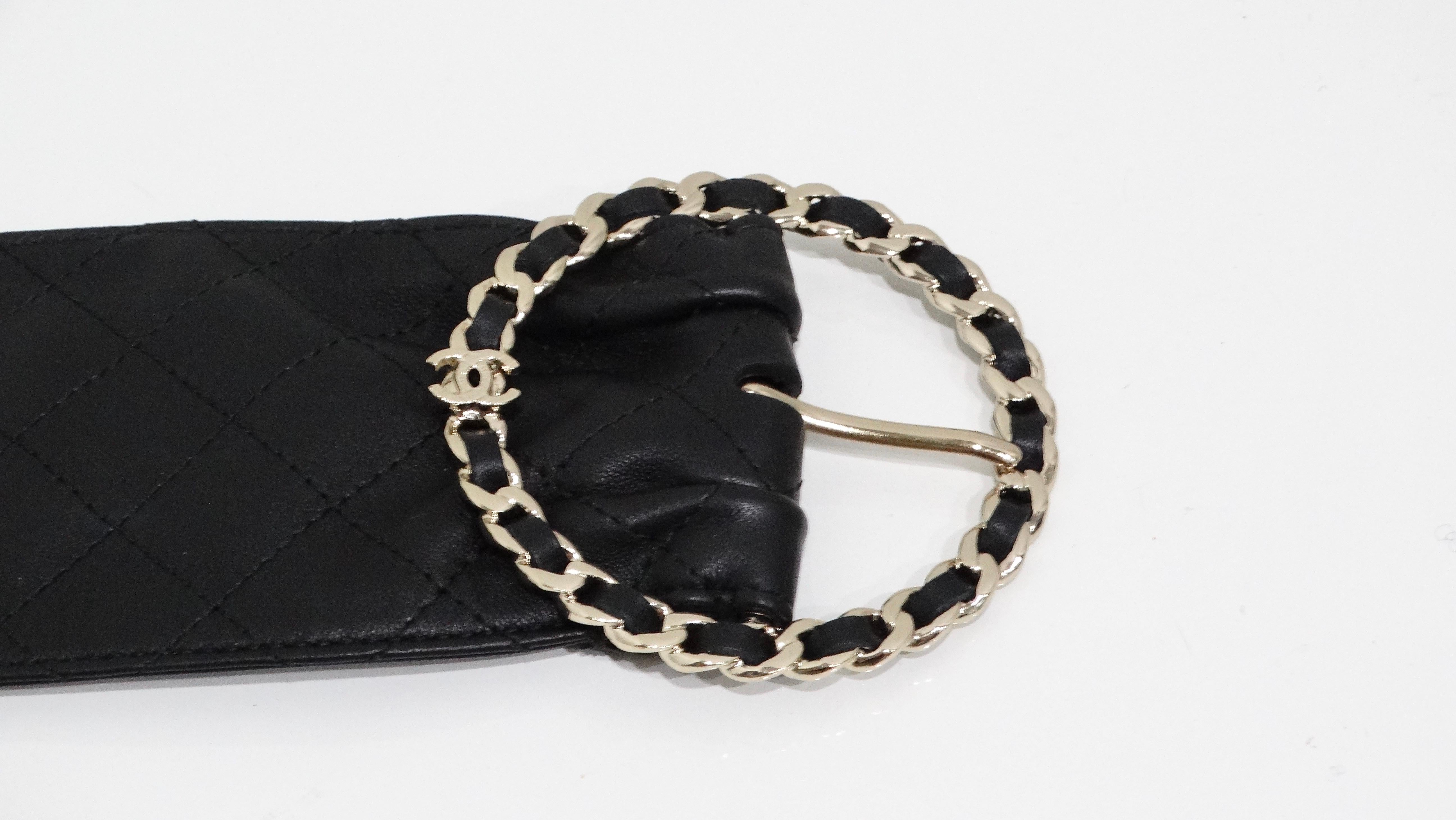 Questa cintura nera trapuntata in pelle d'agnello di Chanel è un accessorio lussuoso ed elegante, caratterizzato dall'iconica maestria del marchio. Il pezzo forte è costituito da una fibbia circolare, intrecciata con pelle e metallo nella tonalità