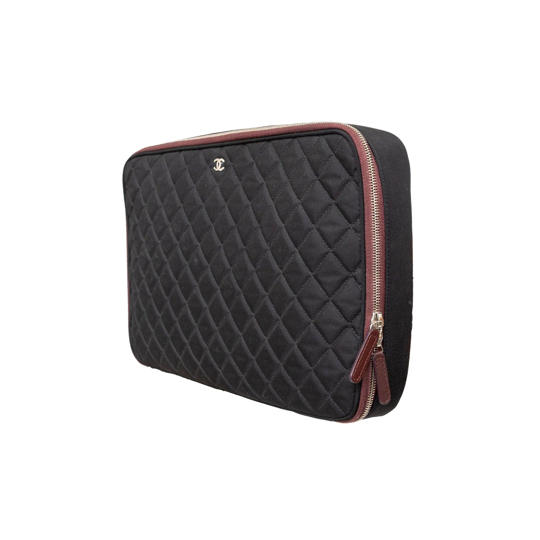 Custodia trapuntata per laptop Chanel della collezione Natale 2012 in nylon nero con finiture argentate, logo CC a incastro, fodera bordeaux e chiusura con zip.
 Inclusione: scatola. 
 Osservazioni: ci sono alcune macchie all'interno. 
 Materiale: