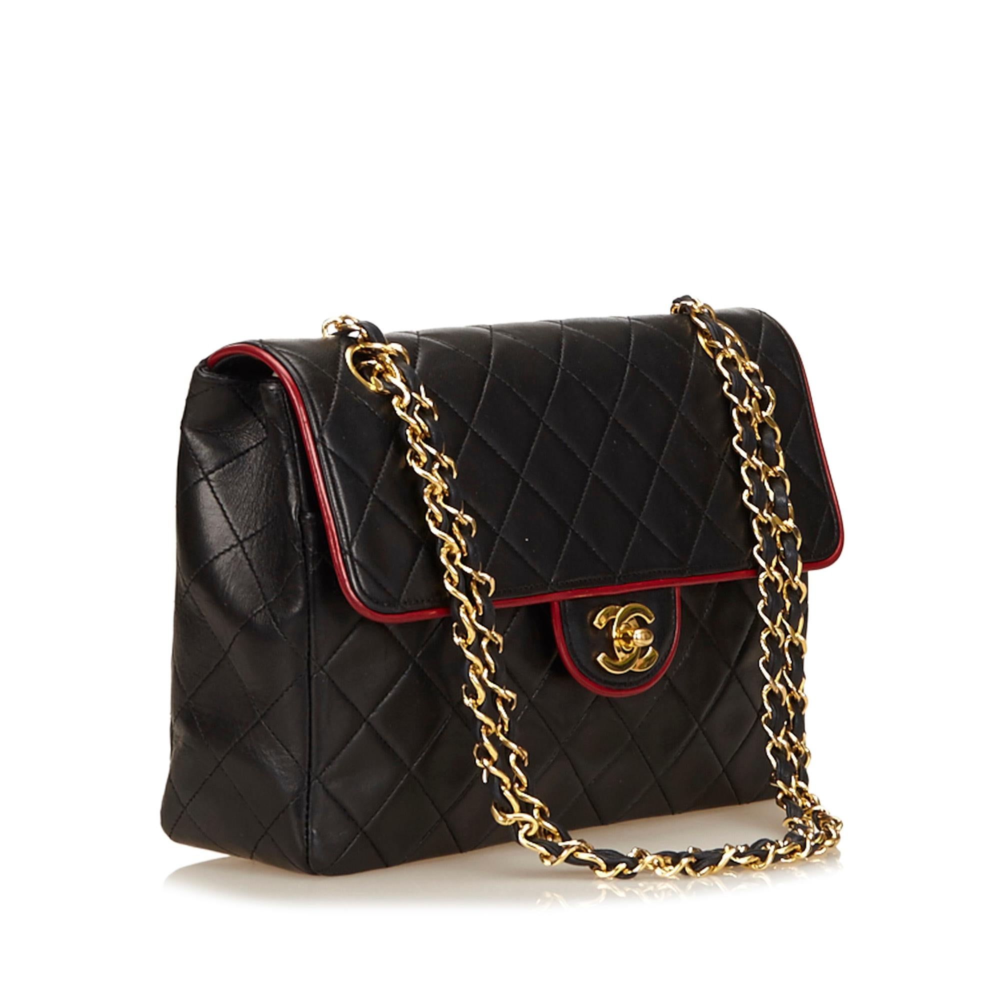This Chanel shoulder bag features a matelasse quilted leather body trimmed with red piping, a thick double gold-tone shoulder chain, and a front flap with interlocking CCs and a twist lock closure.

Serial number: 1393525
