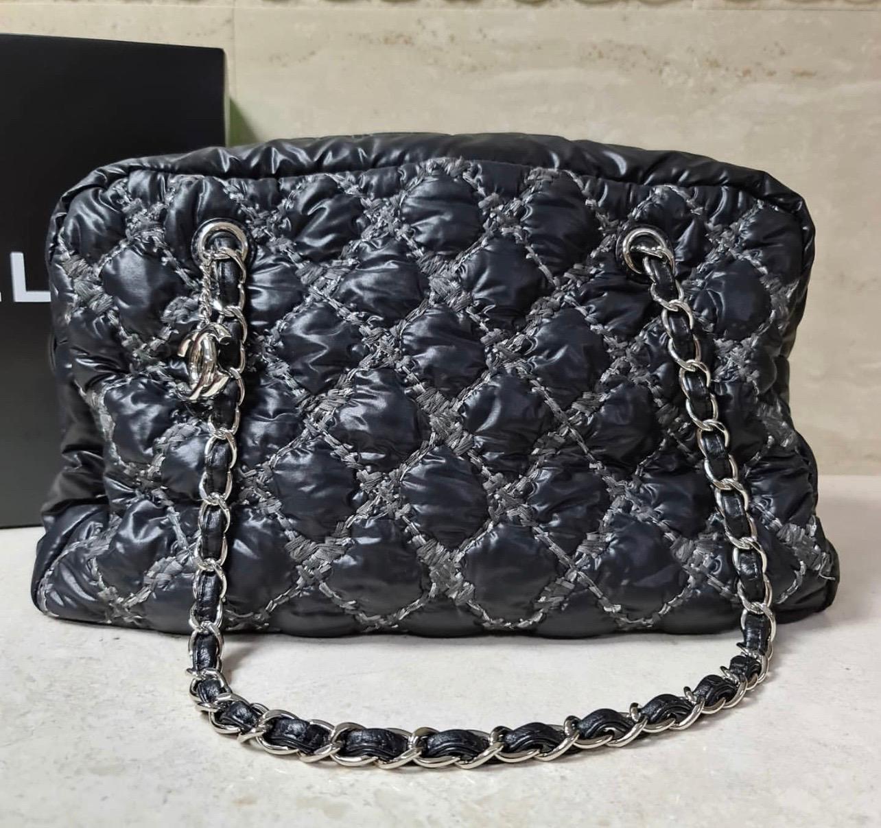 CHANEL Nylon Quilted Tweed on Stitch Zip Tote Bag.

Black nylon with diamond quilted stitches of tweed.

Gold chain link shoulder straps hanging gold Chanel CC pendant. Zipper opens with fabric interior with zipper and patch pockets.

A lot of room