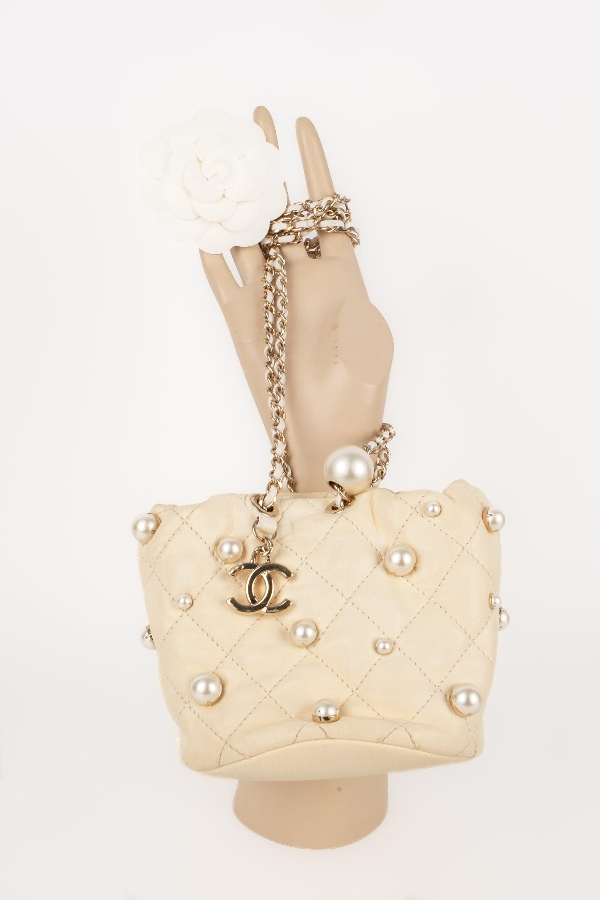 Chanel - (Made in Italy) Quilted off-white calfskin bucket bag ornamented with costume white pearls appliqués. Adjustable crossbody strap. Piece with its Hologram. 2001 Spring-Summer Collection under the direction of Virginie Viard. To be mentioned,