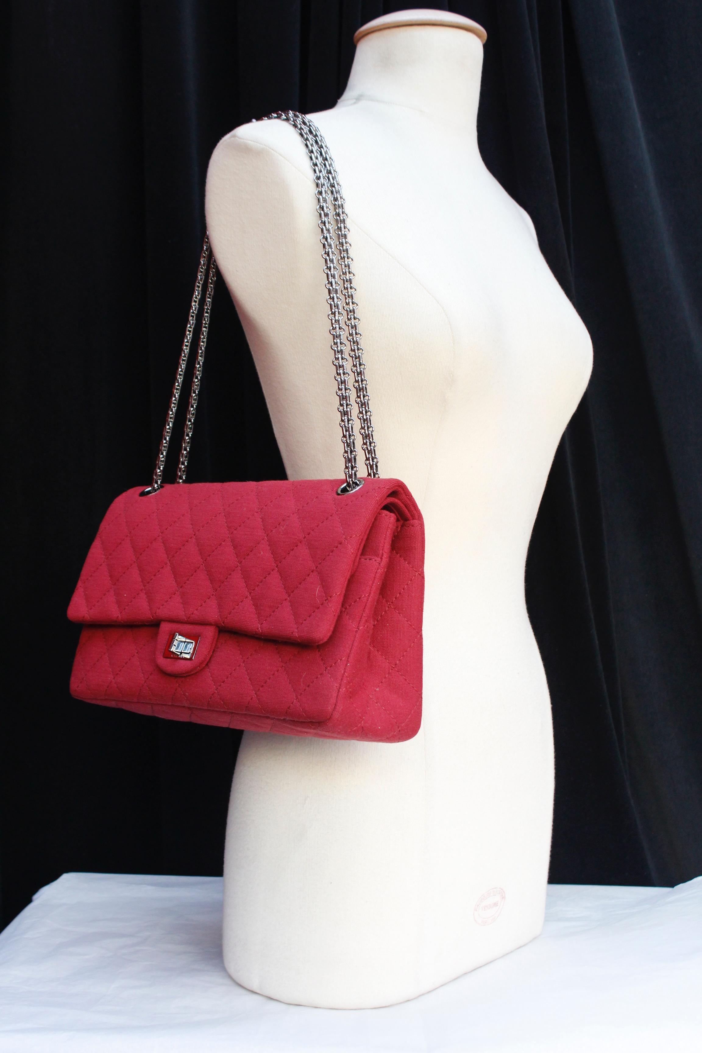 CHANEL (Made in France)  Gorgeous quilted red jersey bag, model 2.55, with dark silvery hardware. It features a twist lock and a double chain handle, a back patch pocket, and a double flap. The larger flap has a small zipped pocket. Cherry red