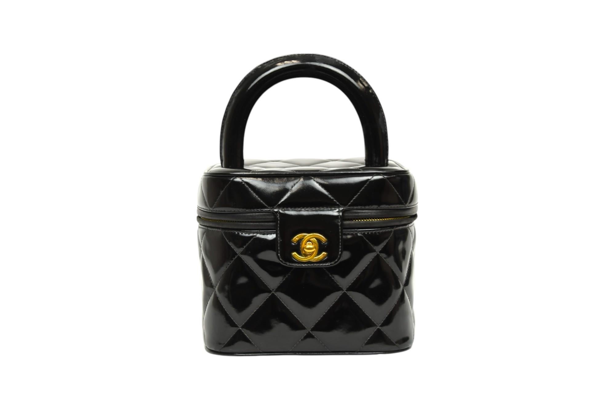 A rare and collectible piece, this Chanel vanity top handle bag hails from the 1996–1997 collection and is crafted in sleek black quilted patent leather. The structured silhouette, inspired by vintage beauty cases, features a smooth rounded top