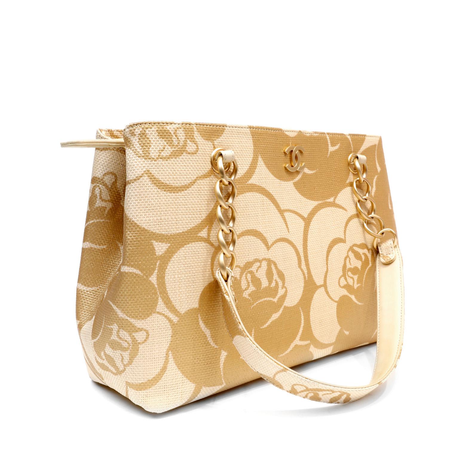 This authentic Chanel Raffia Camellia Tote is in pristine condition.  Elegant for the beach or town, this is a beautiful piece for any holiday. Beige and tan raffia tote with swirling camellia flower abstract pattern.  Matte gold interlocking CC