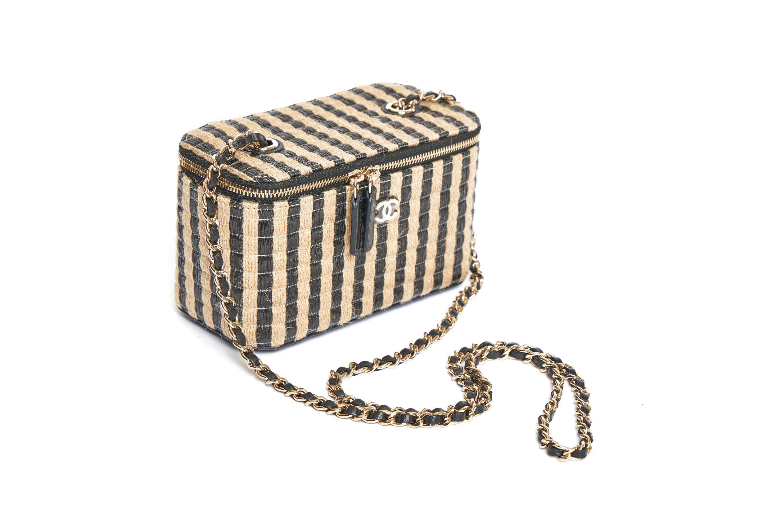 Mini Chanel Raffia Vanity bag with black stripes from the 2020 collection. It’s a crossbody bag and the shoulder drop of the leather-threaded gold chain is 22’. On front of the bag is a small CC logo which is still covered in plastic. The interior