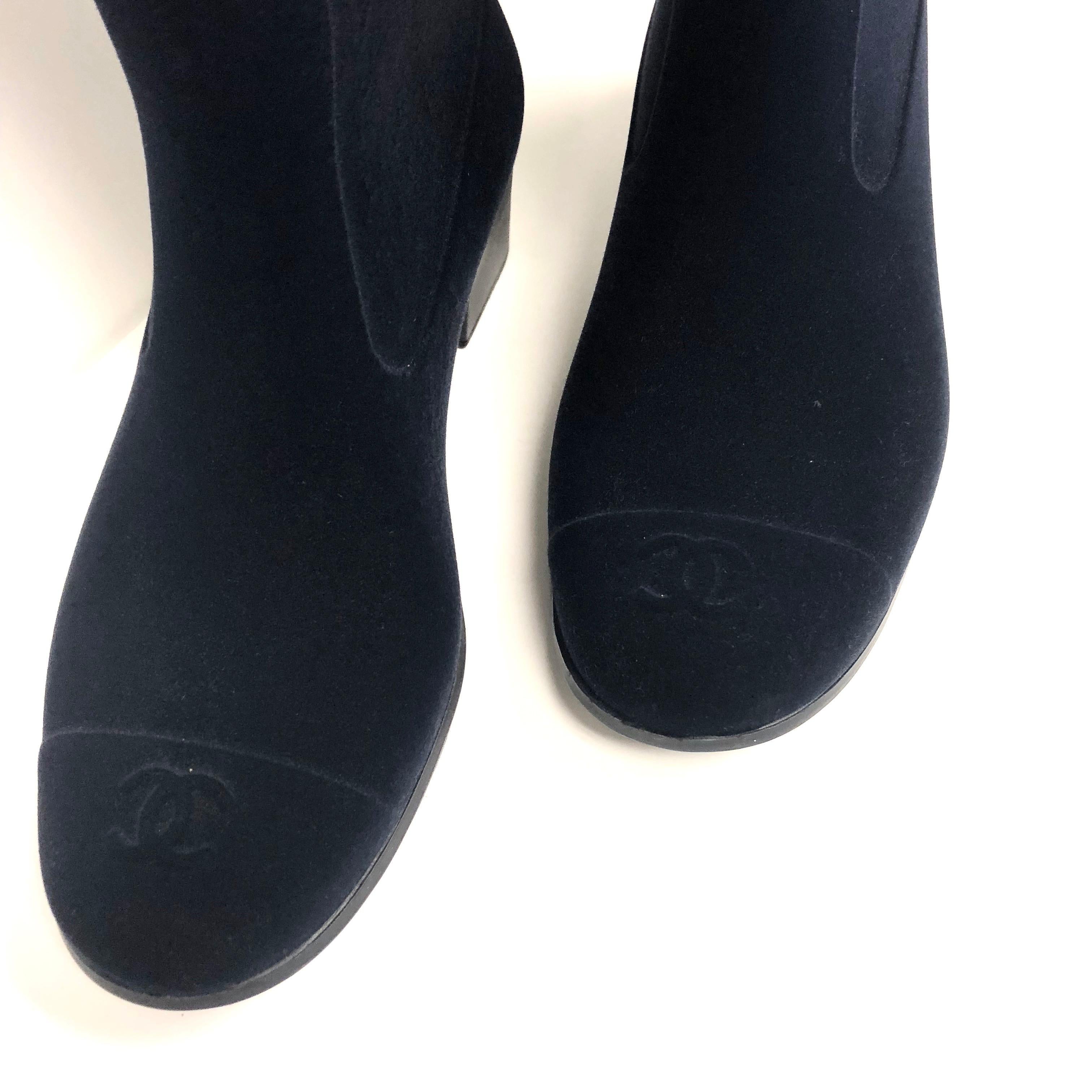 CHANEL dark navy color rain boots with suede like exterior. They are each decorated with two camellias and a gold tone CC logo on the sides. 
Cap toe design removable leather insole. Rubber sole with the Chanel logo embossed.
Heels: 1 1/2