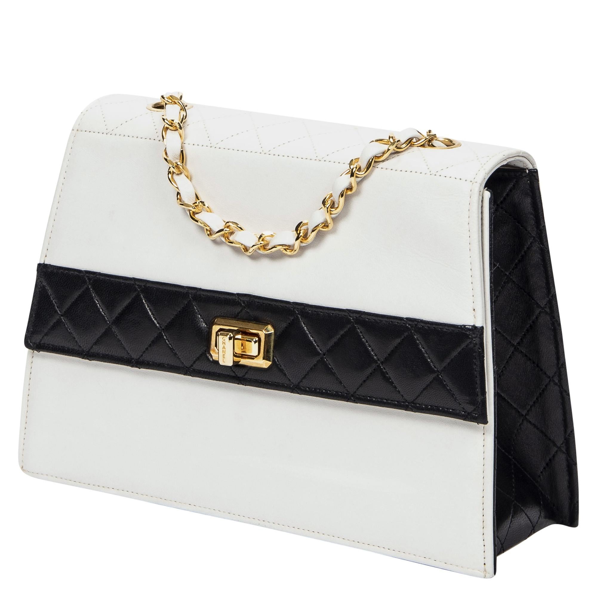 Chanel's Rare 1989 Vintage Bicolor Flap Bag with Pouch is a timeless piece in elegant white lambskin leather, accented with luxurious gold hardware. The classic turn-lock closure opens to a sleek leather interior, providing a sophisticated space for