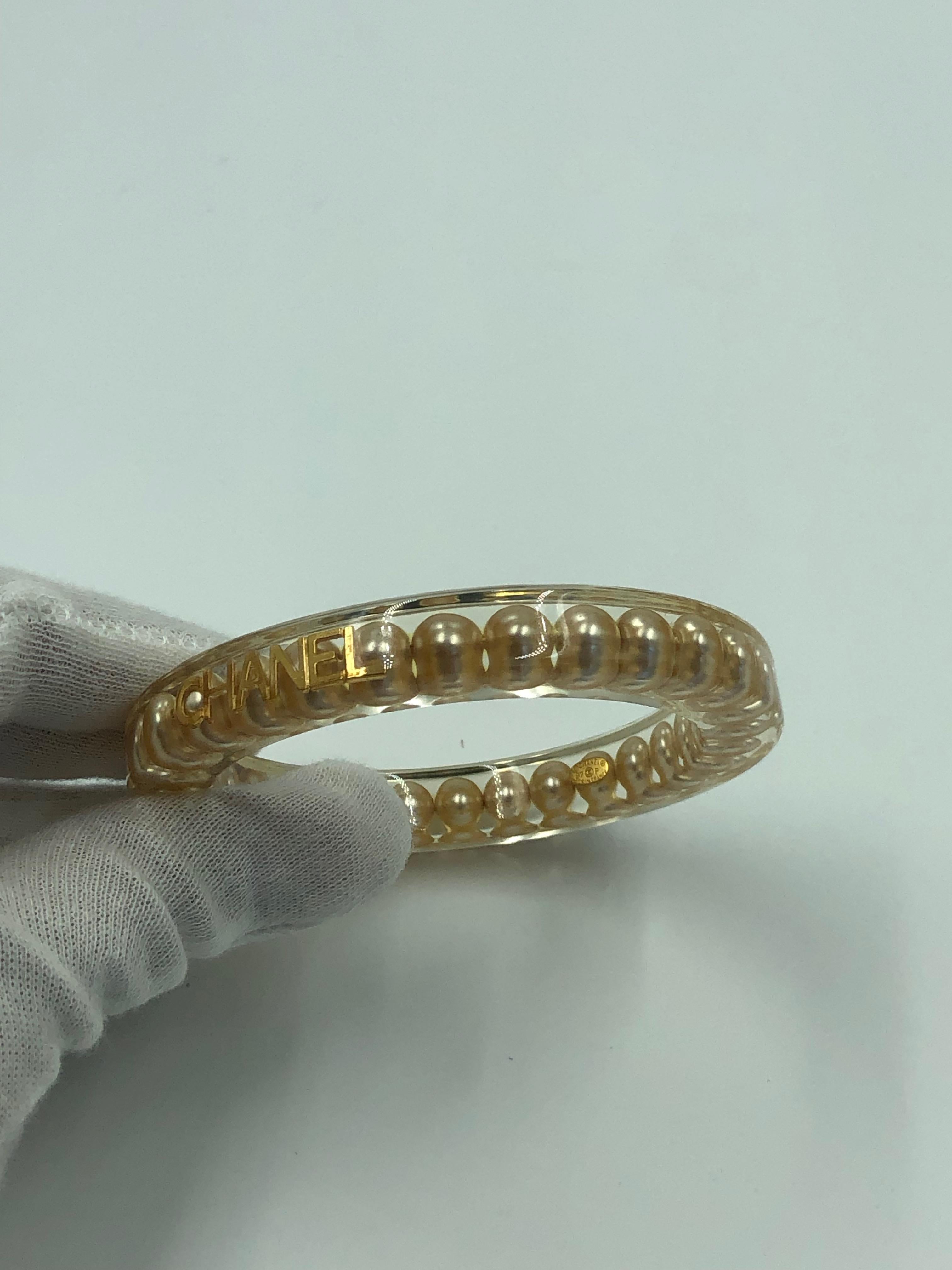Raro braccialetto autentico Chanel in lucite con perle finte. 
Accessori con logo in tonalità oro. 
Dalla collezione primavera 1997.
Nessun segno visibile di usura.

*MISURE*
Circonferenza interna: 7 1/2