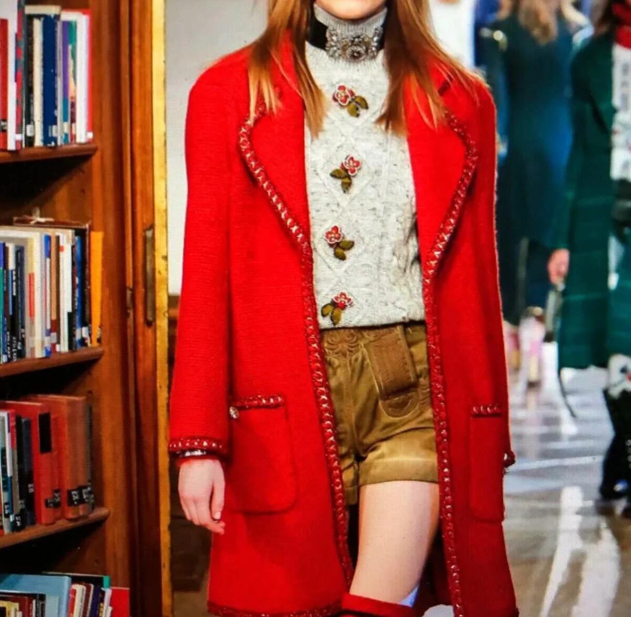 2015 Paris-Salzburg Metiers d'Art
Chanel Tweed-Mantel aus rotem Alpaka (76%), Wolle (19%) und Nylon (5%). Mit Kettenbesatz, geknöpften Ärmeln und zwei aufgesetzten Taschen mit Knöpfen auf der Vorderseite. Wird mit einem Haken auf der Vorderseite