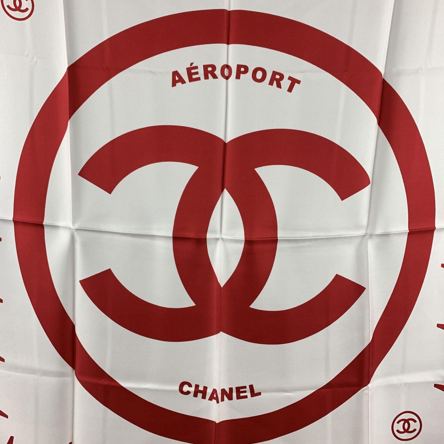 Chanel 'Aeroport' silk scarf in red and white colors from the 2016 Airline collection. Contrast dark borders. Big Chanel CC logo in the center, surrounded by red and white airplanes. Rolled edges. Composition: 100% Silk. Measurements: 36 x 36 inches