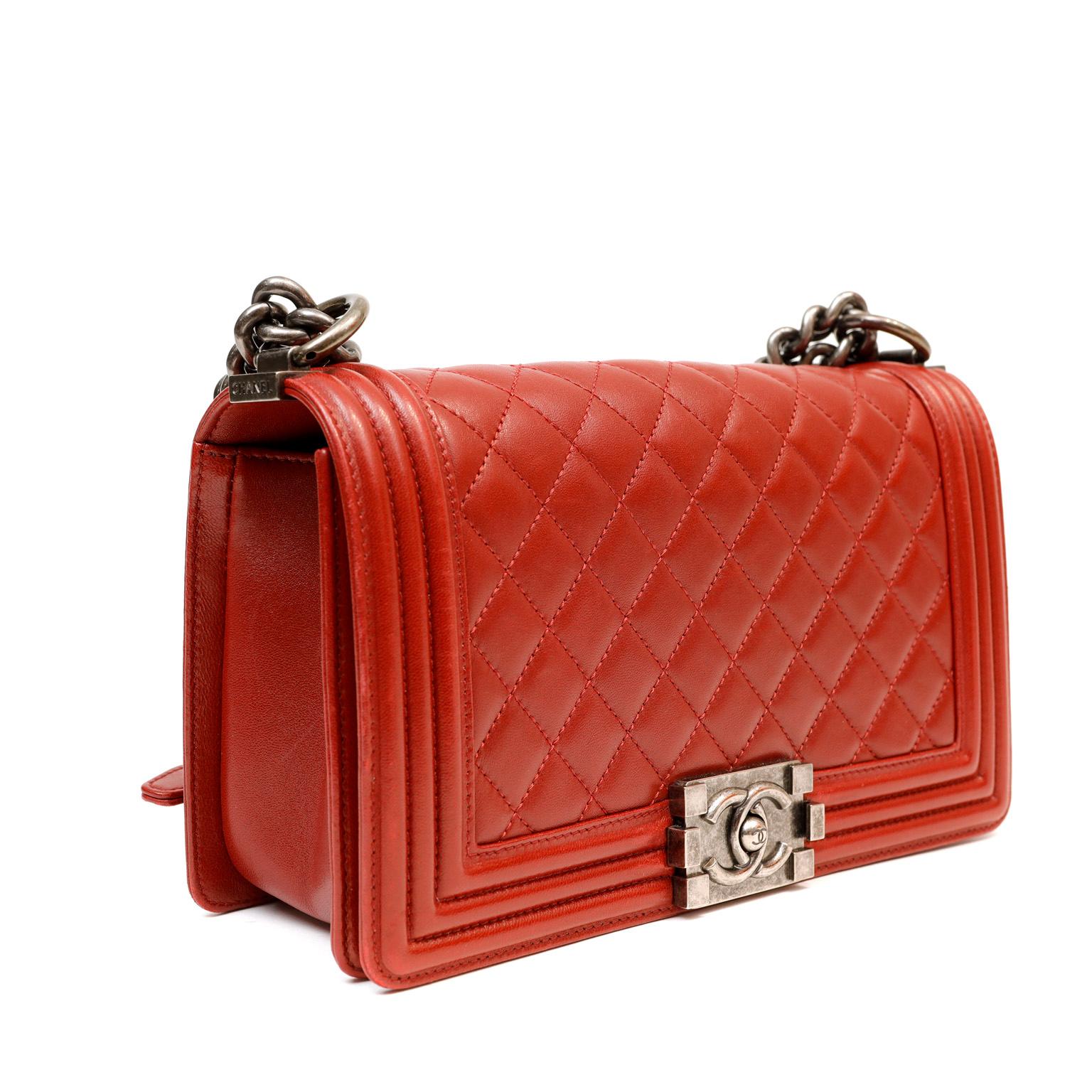 This authentic Chanel Red Calfskin Boy Bag is in pristine condition.  The updated design is structured and edgy with a versatility that makes it extremely popular.  True red calfskin is quilted in signature Chanel diamond stitched pattern.  Boy Bag