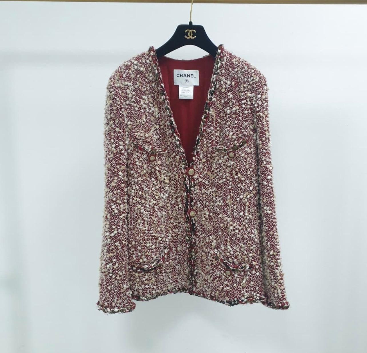 From the Paris-Dallas 2014 collection comes this Chanel Red/Ecru Tweed Jacket!
Composed of a beautiful wool blended boucle tweed, this jacket has a collarless style with a braided trim.
With chic star engraved goldtone buttons, this jacket is an