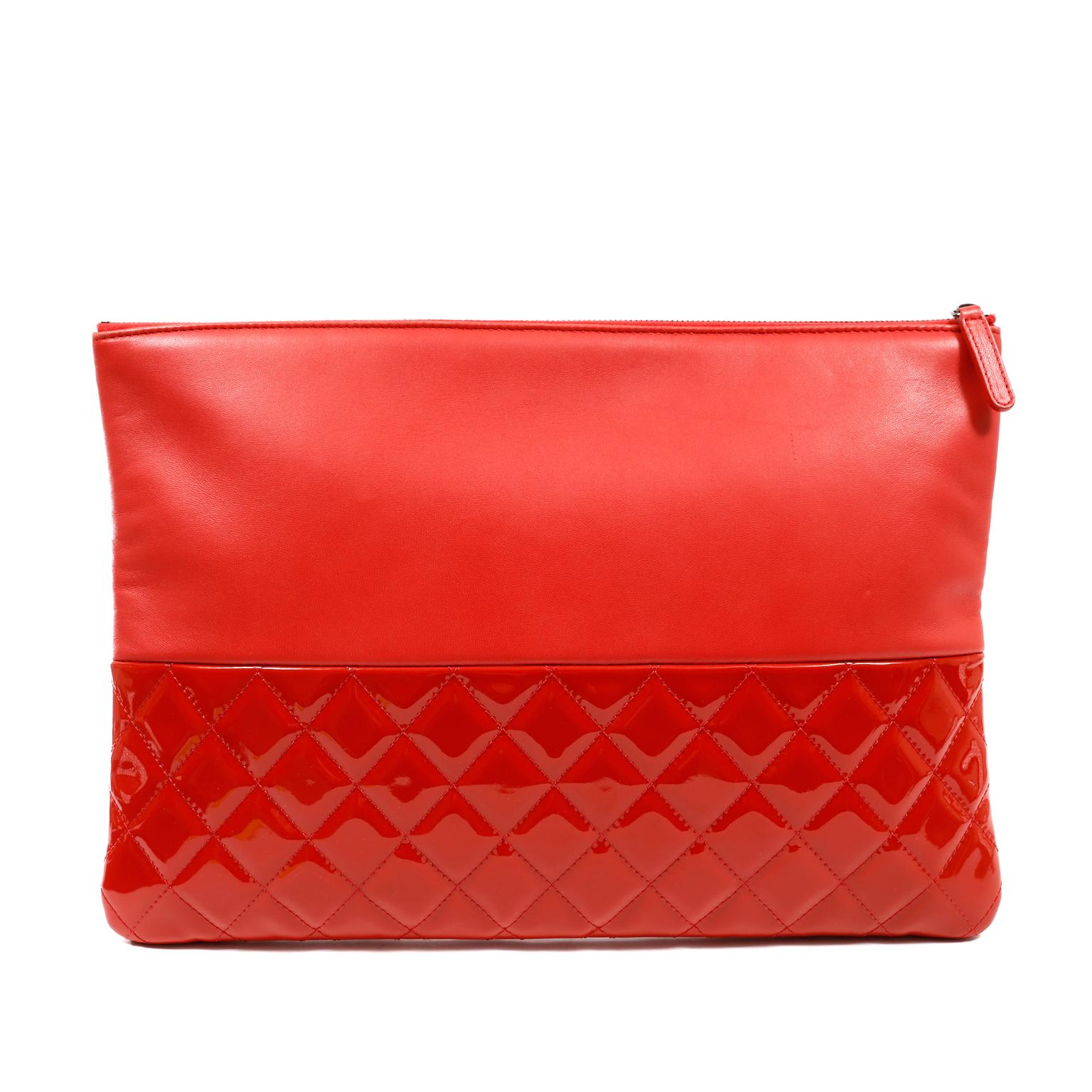 This authentic Chanel Red Lambskin and Patent Leather Clutch is in excellent condition.  The simple silhouette gets a boost with a mixed texture and fiery red color.  
Lipstick red smooth lambskin sits atop a quilted patent leather bottom.  Zippered