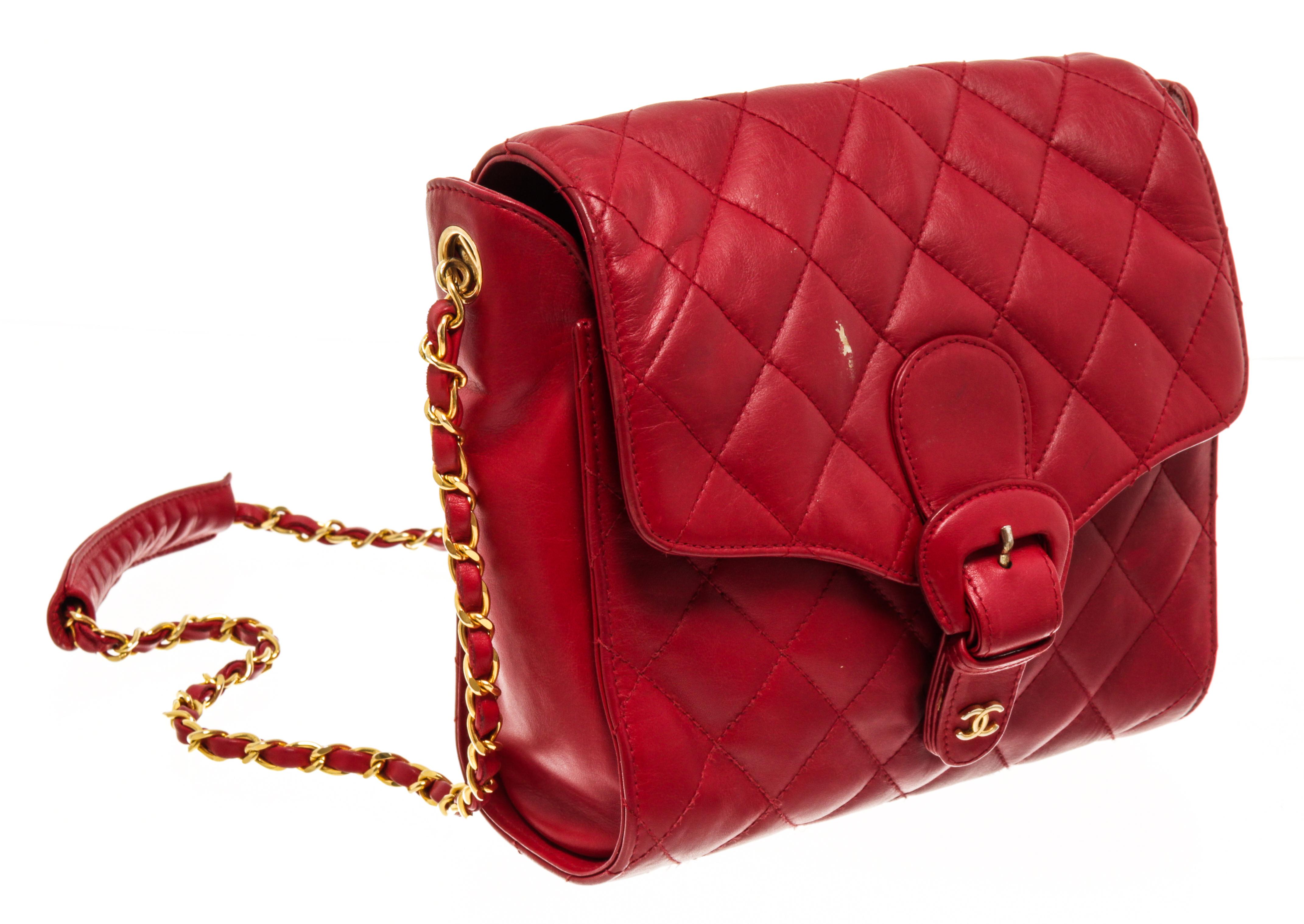 Chanel red leather chain buckle flap shoulder bag with red quilted leather exterior, red leather lining, gold-tone hardware, a long chain with shoulder pad, buckle closure, one main compartment, and one interior zip pocket. There is a scratch on the