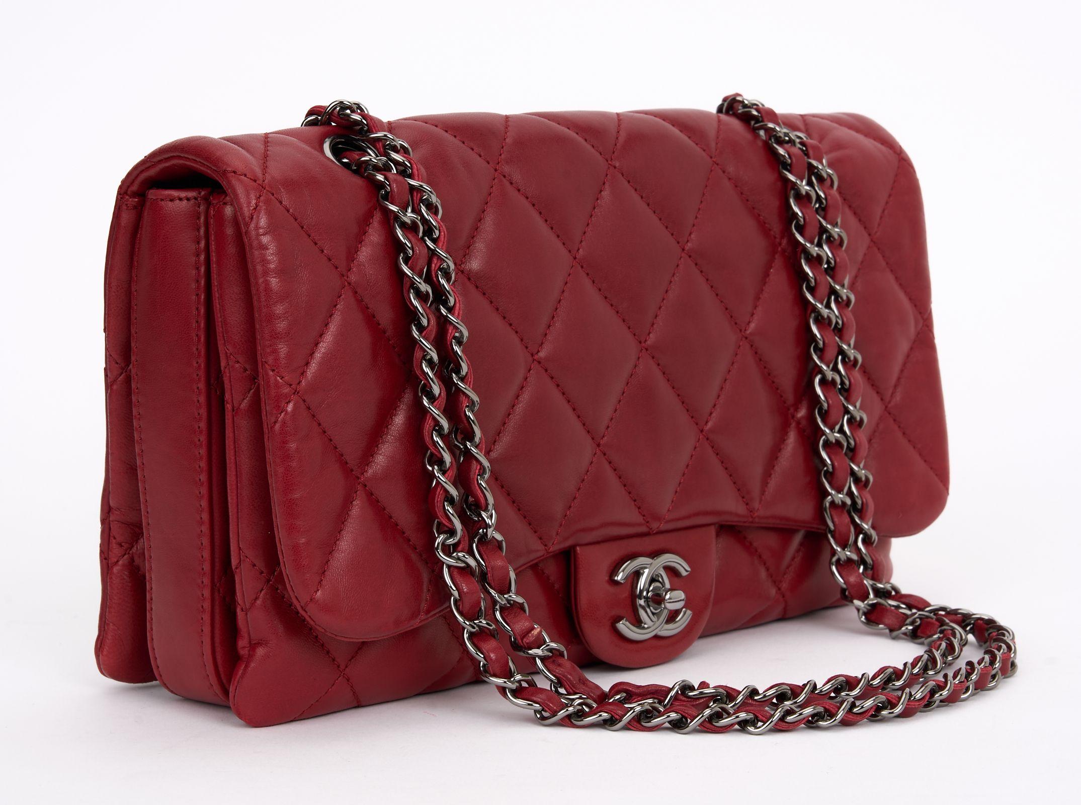 This Chanel Maxi 3 Accordion Flap Bag features a quilted red lambskin leather body, a silver leather woven chain strap, a front flap with CC turn-lock closure, an exterior back slip pocket, interior open compartments, and an interior zip pocket. Can