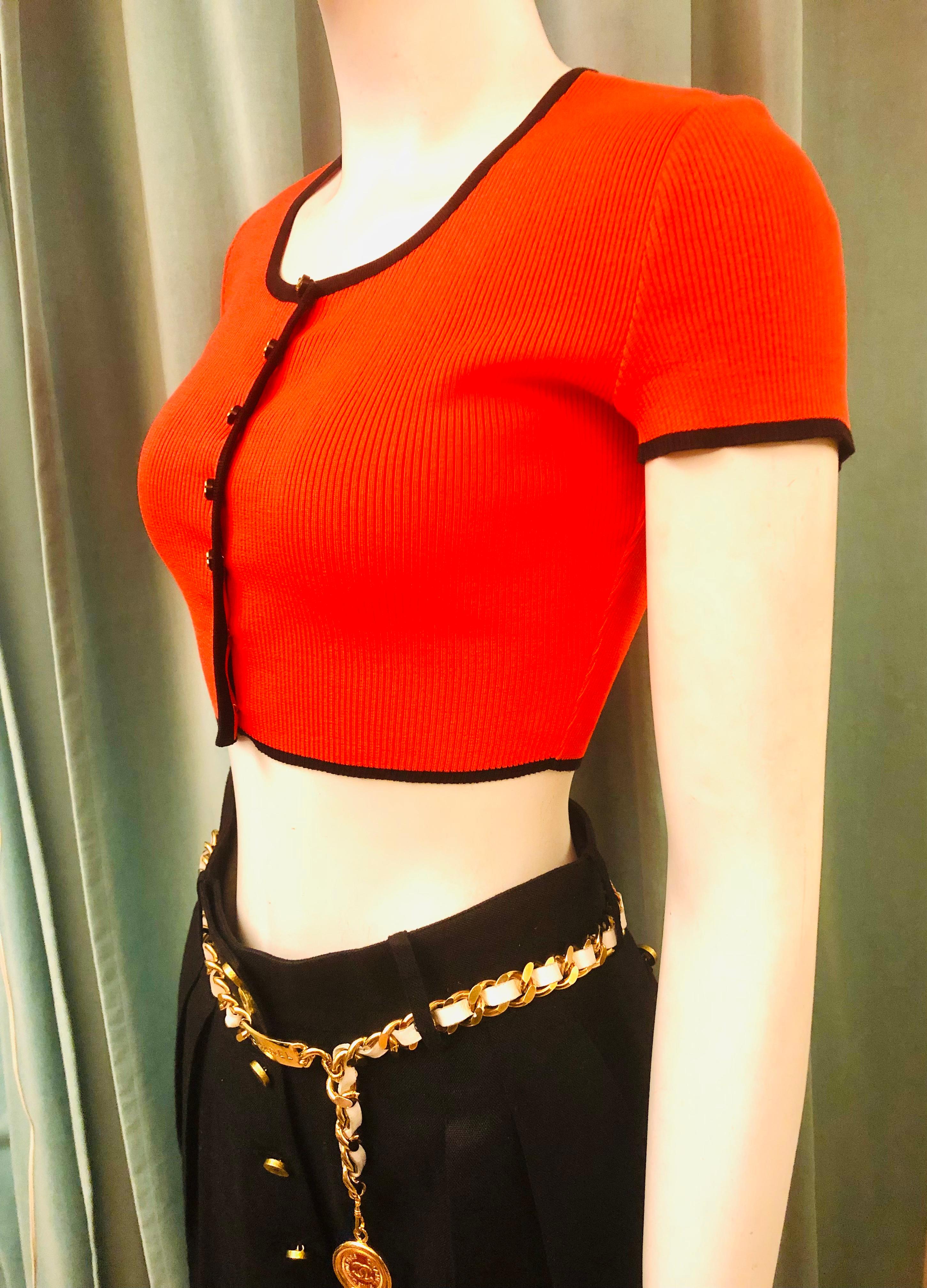 - Este icónico top Chanel de color rojo/naranja brillante con ribetes negros pertenece a la colección Primavera/Verano 1995. ¡Está en excelentes condiciones!

- Cierre de los botones 