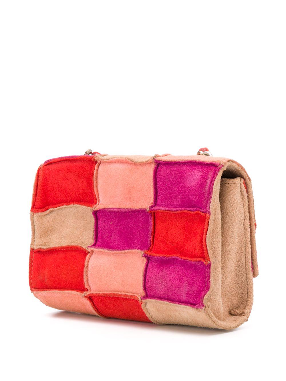 Crafted in France from luxurious suede in a vibrant palette of red, magenta, rust and camel, this timeless mini crossbody bag by Chanel features a square, patchwork paneled exterior, a rear slip pocket a red leather-laced chain shoulder strap that