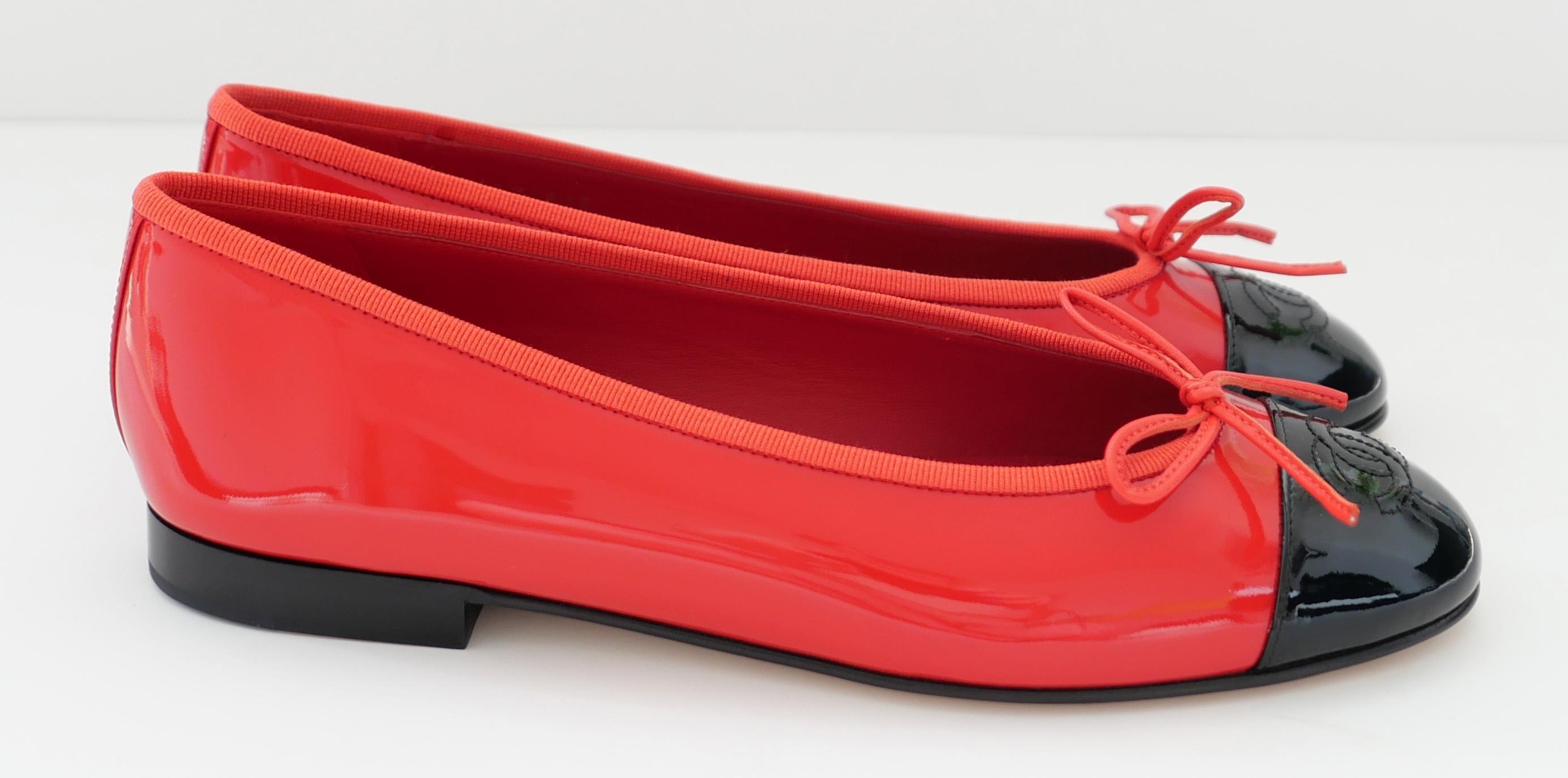 Superbes ballerines Chanel en vernis rouge. Neuf avec boîte et 2 x sacs à poussière. 
Fabriqués en cuir verni rouge vif avec embouts en CC verni noir surpiqués, bordures en gros-grain et semelles en cuir. Taille 38. L'intérieur du talon mesure