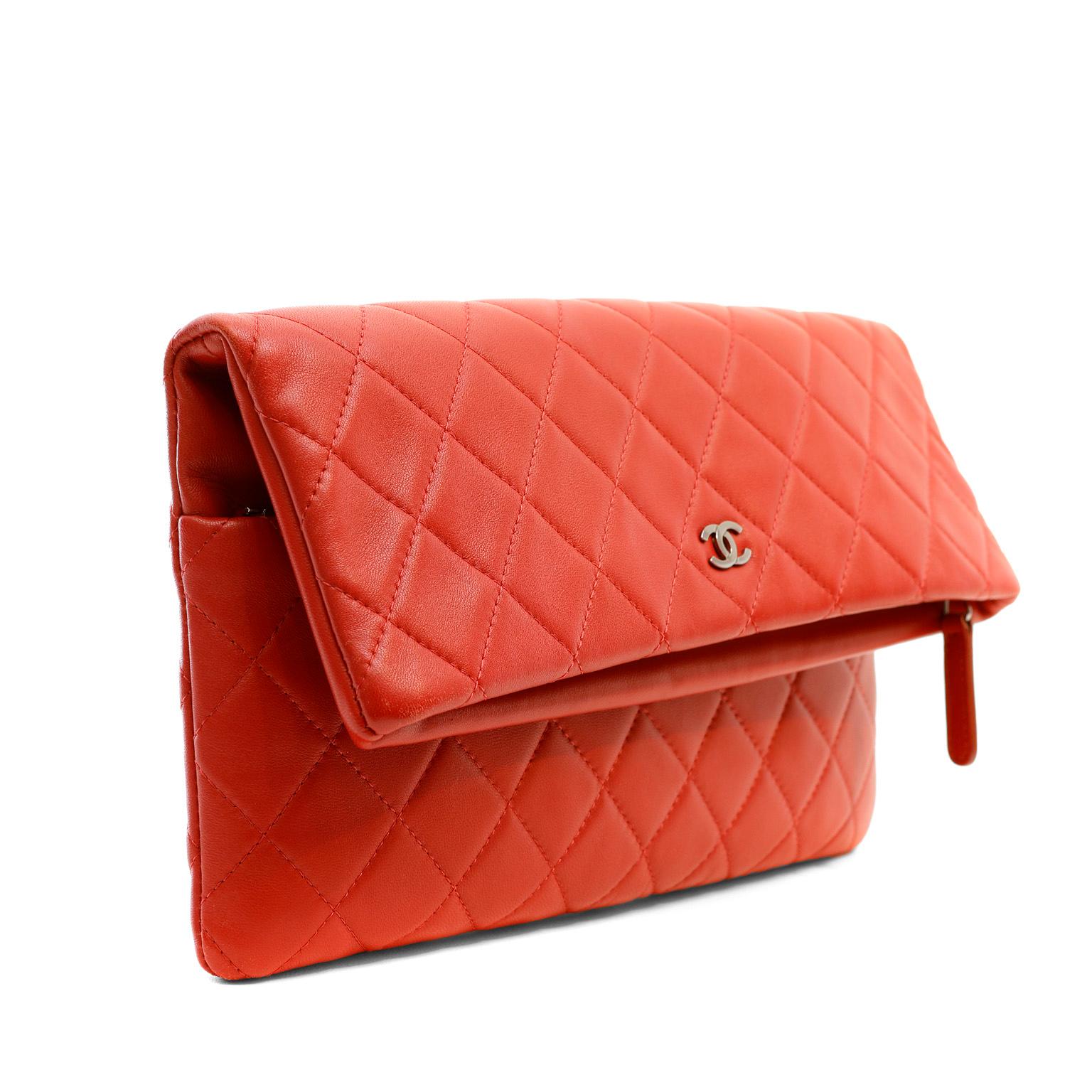 This authentic Chanel Red Quilted Lambskin Foldover Clutch is in pristine condition appearing never carried.  Bright lipstick red lambskin is quilted in signature Chanel diamond pattern.  Secure silver tone zippered top with foldover. Dust bag