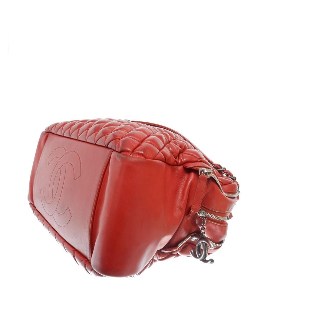 Red quilted lambskin leather in the signature diamond stich pattern features interlocking CC logo, double mademoiselle chain straps, open top with middle magnetic snap closure, fine textile lining interior, one center zip pocket, two compartments,