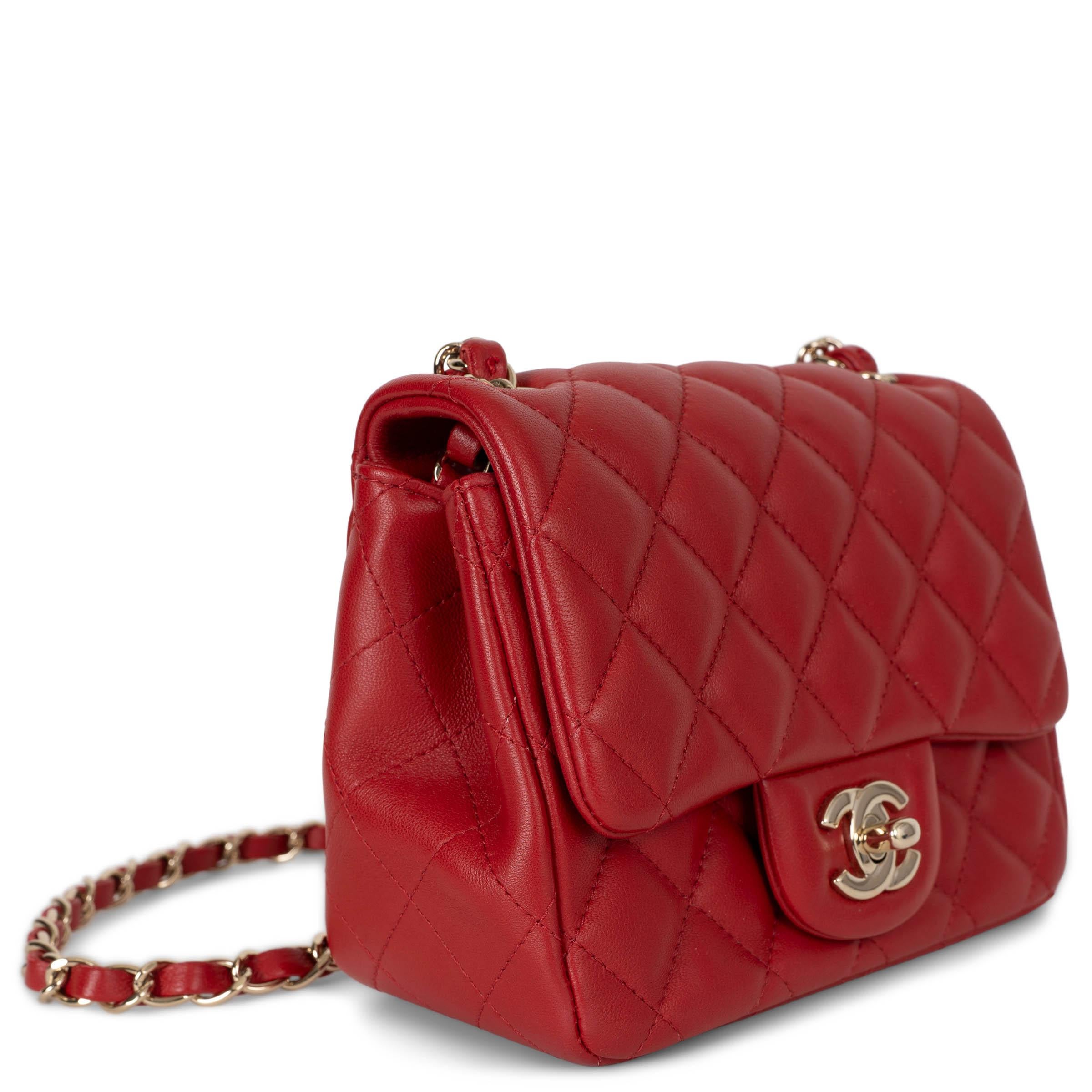 Questa borsa a tracolla Chanel Classic Mini Square, autentica al 100%, è realizzata in pelle d'agnello trapuntata rosso brillante con finiture in oro chiaro. Presenta l'iconica chiusura CC a girello e una tasca aperta sul retro. La patta si apre su