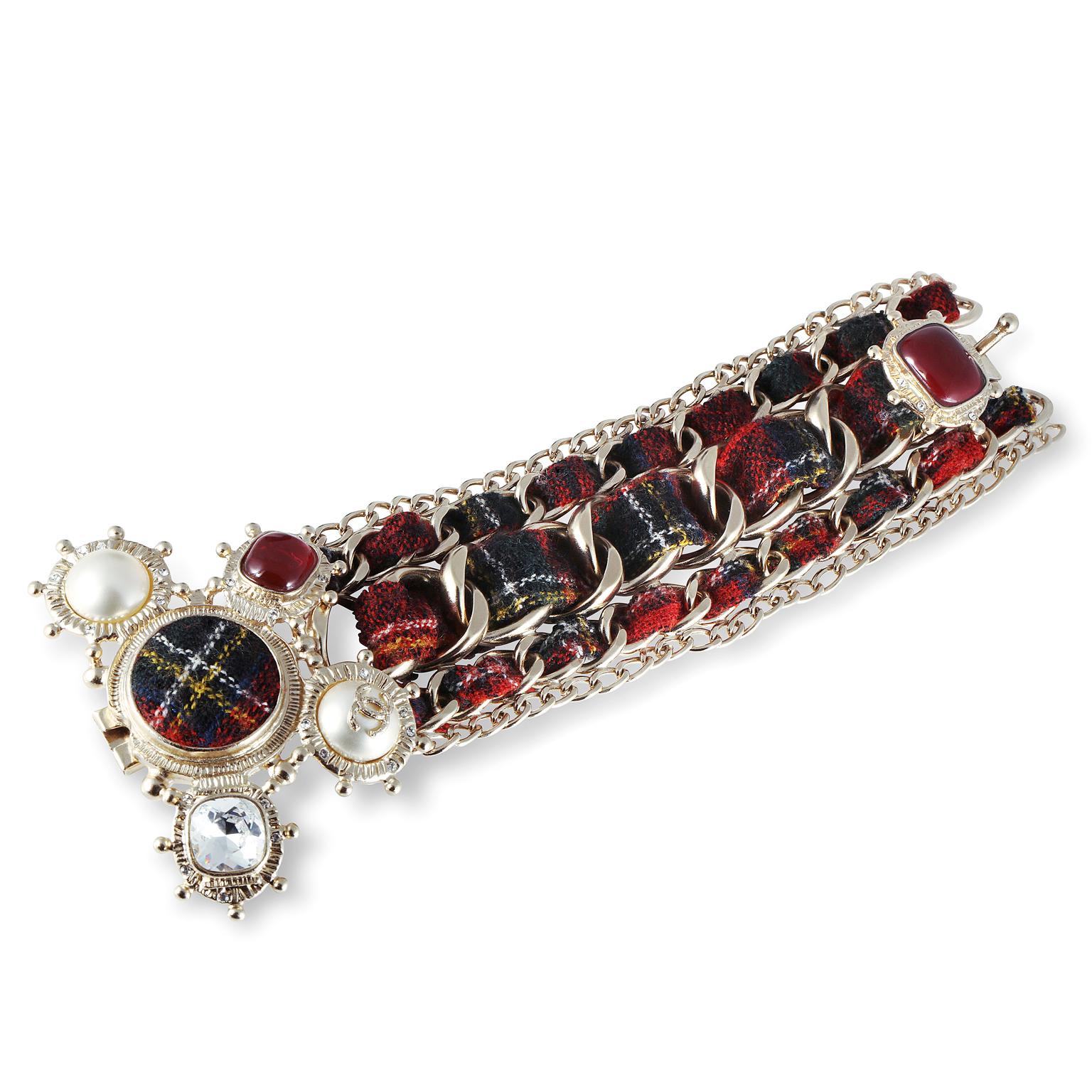 Questo autentico bracciale Chanel Red Tartan Embellished Cuff è in ottime condizioni.  Il tessuto plaid rosso Tartan è intrecciato con catene multiple in oro chiaro.  La chiusura è nascosta dal fermaglio ornato di dettagli.  Perle finte, cristalli e