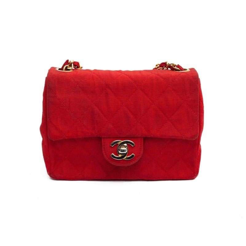 Mini Timeless bag in red quilted fabric. The attributes are in gold metal. Coco Mademoiselle clasp which over time has lost its gilding. The inside of the bag is in good condition, two flat pockets, one of which is zipped, some signs of use (see