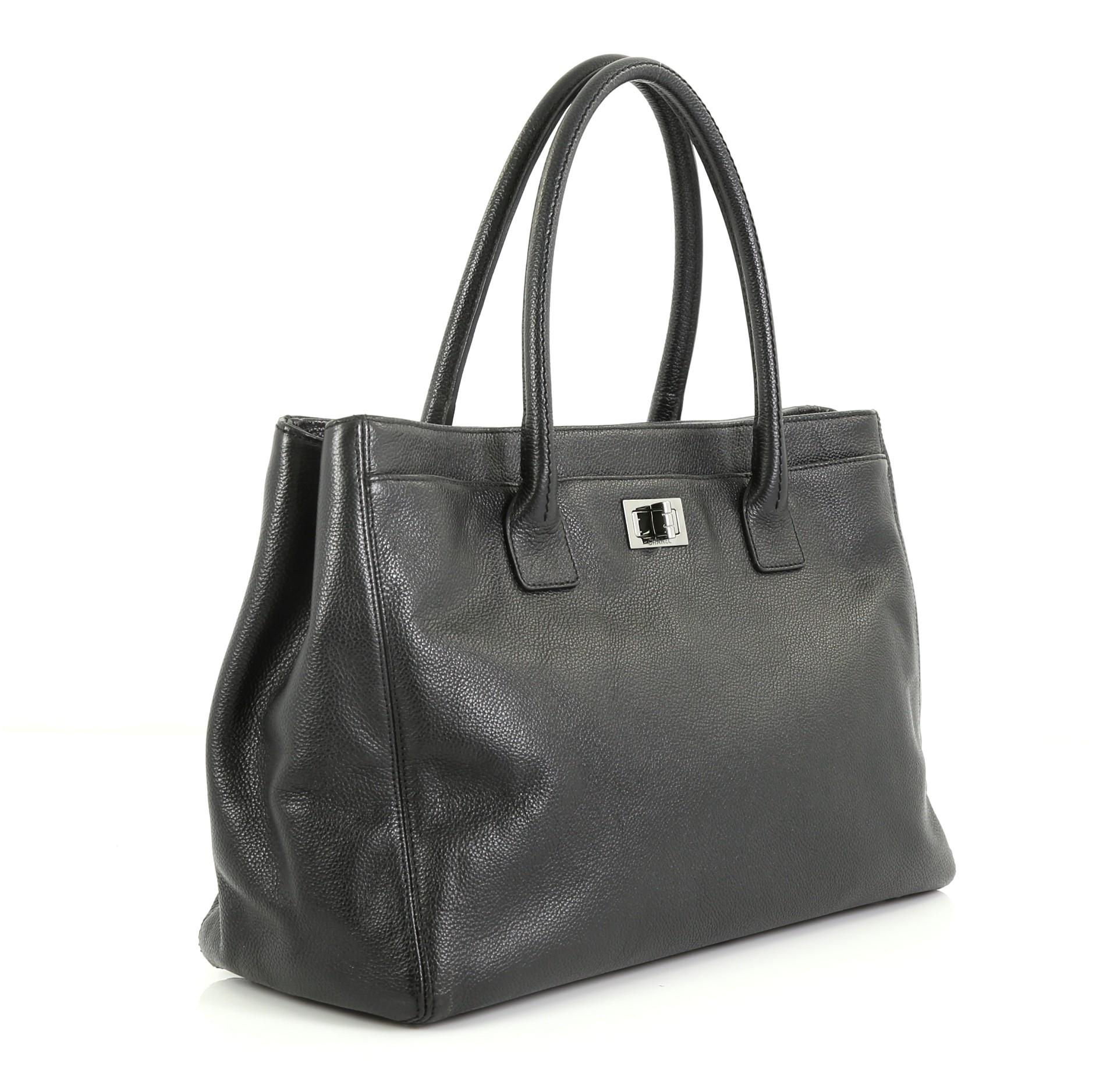 This Chanel Reissue Cerf Executive Tote Leather Medium, crafted in black leather, features dual rolled leather handles, front pocket with mademoiselle turn-lock closure, exterior back pocket, and silver-tone hardware. Its magnetic snap closures open