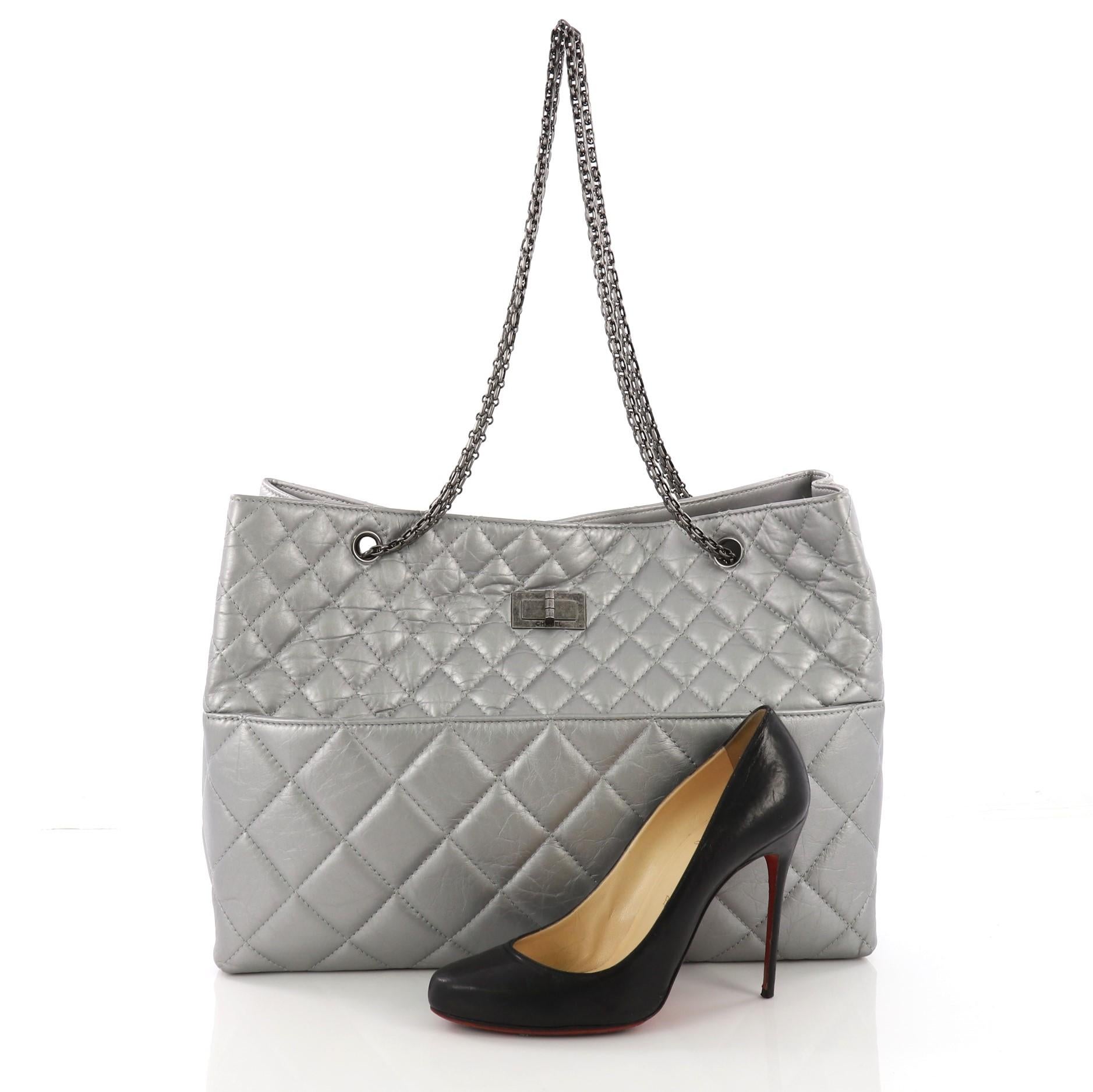 This Chanel Reissue Tote Quilted Aged Calfskin East West, crafted in silver quilted aged calfskin leather, features iconic mademoiselle chain straps, front and back slip pockets, and aged silver-tone hardware. Its magnetic closure opens to a gray