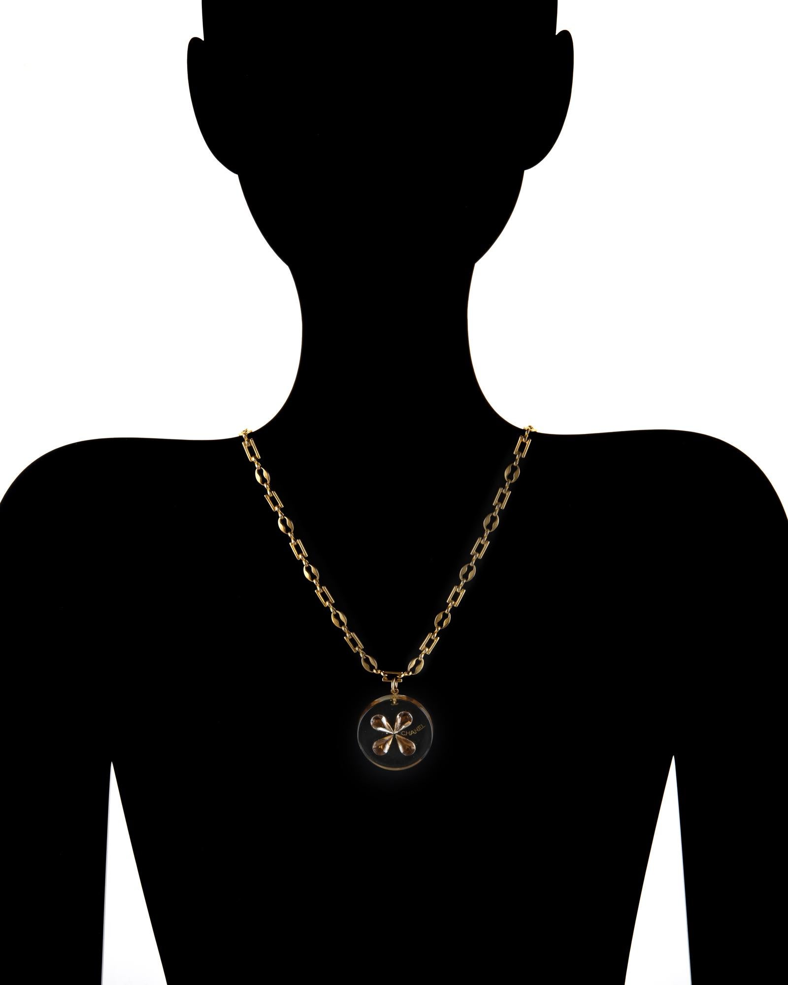 Stylish Chanel pendant necklace crafted in yellow gold tone, circa 2001 

The resin pendant measures 36.5mm (1.43 inches) and is inset with a cognac hued four leaf clover faux jewel design. The chain features an alternating pattern of mariner and