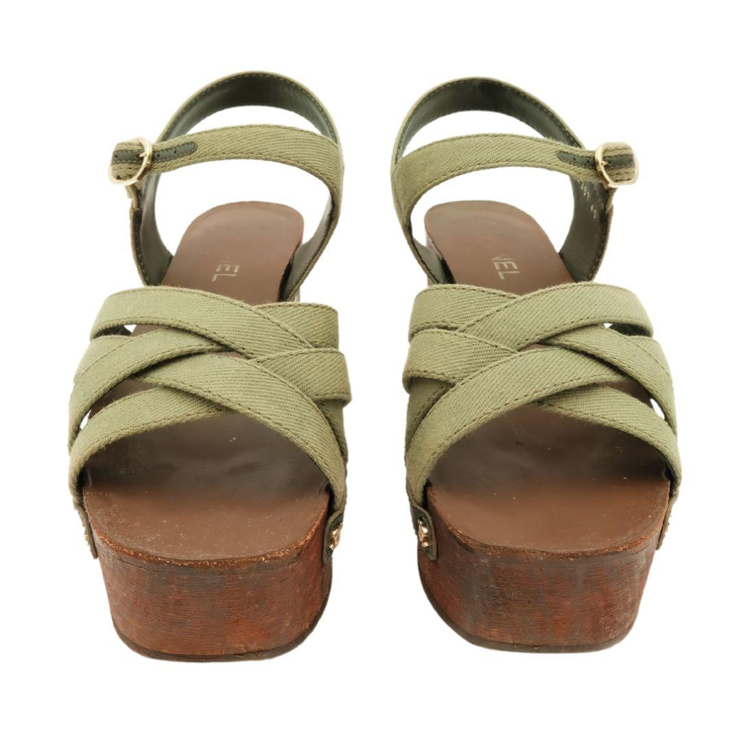 These khaki green wooden platform clog sandals are a commercial piece from the Chanel Cuba Collection for Resort 2017.

Features thick interwoven canvas straps at the front of shoe and ankle straps fastened with a front buckle.

The sides of the