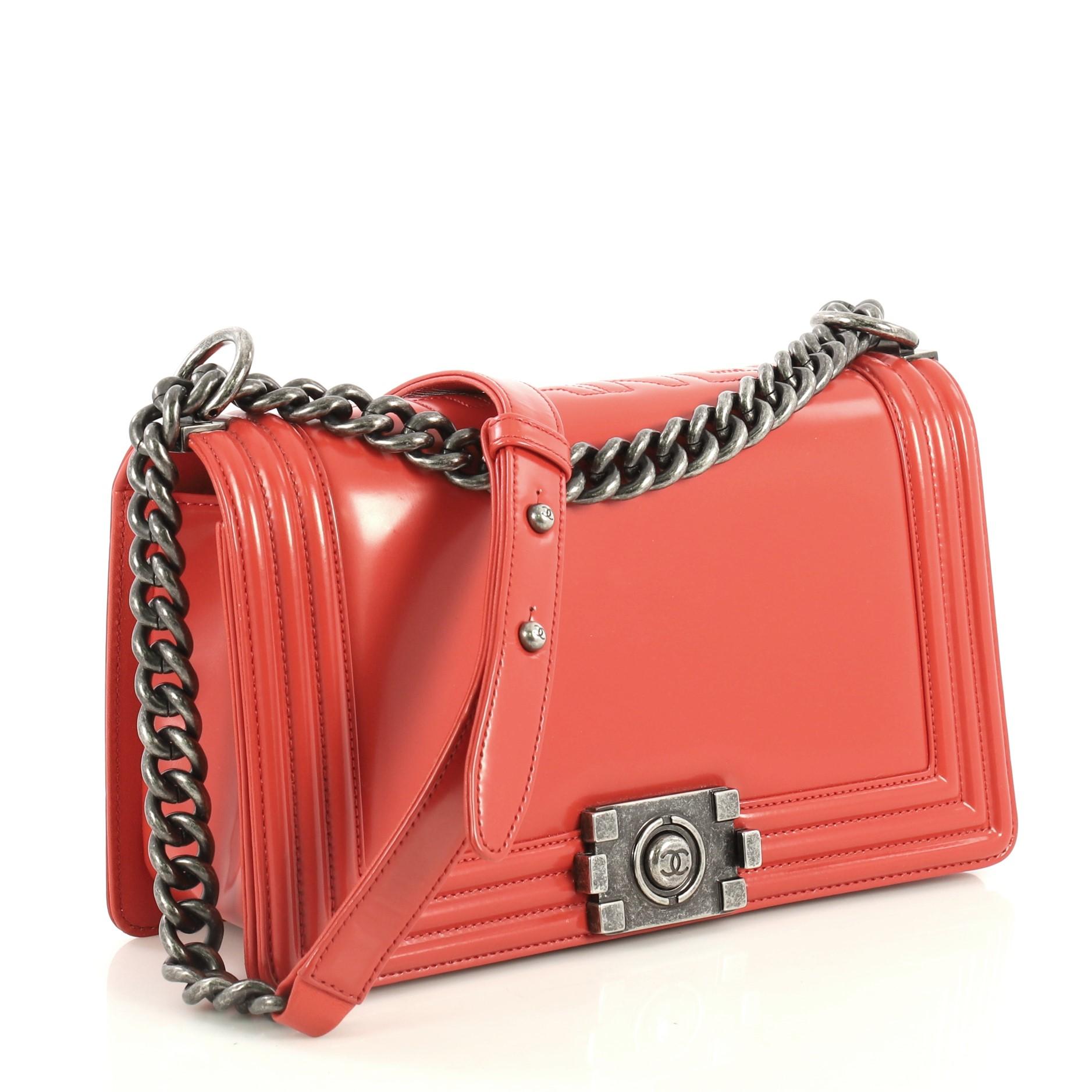 This Chanel Reverso Boy Flap Bag Glazed Calfskin Old Medium, crafted in red glazed calfskin leather, features chain link strap with leather pad and aged silver-tone hardware. Its CC boy push-lock closure opens to a red fabric interior with slip