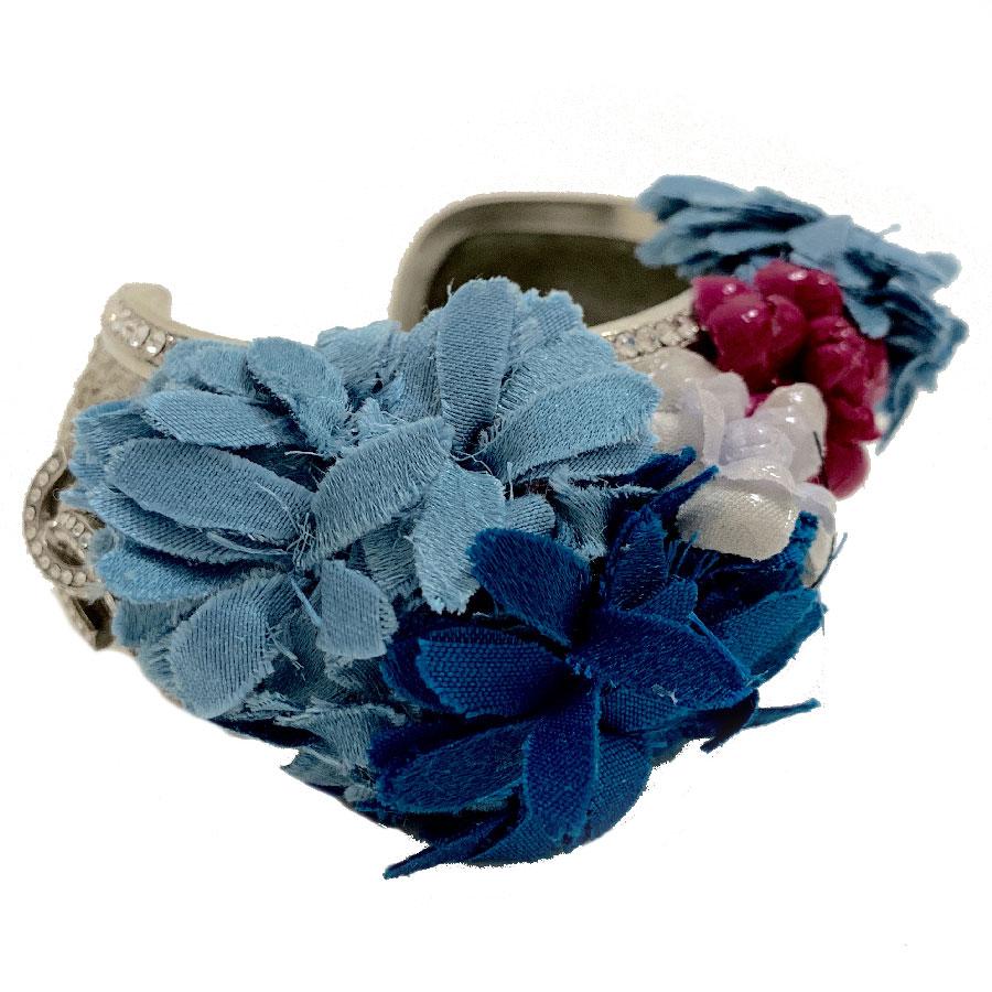Couture, this CHANEL jewel is just magnificent. It is a bracelet from CHANEL fashion shows, in silver metal, rhinestones, CC and colored flowers in fabric and plastic. The interior is in glitter resin. Fragile jewel at the fabric flowers.
It is in