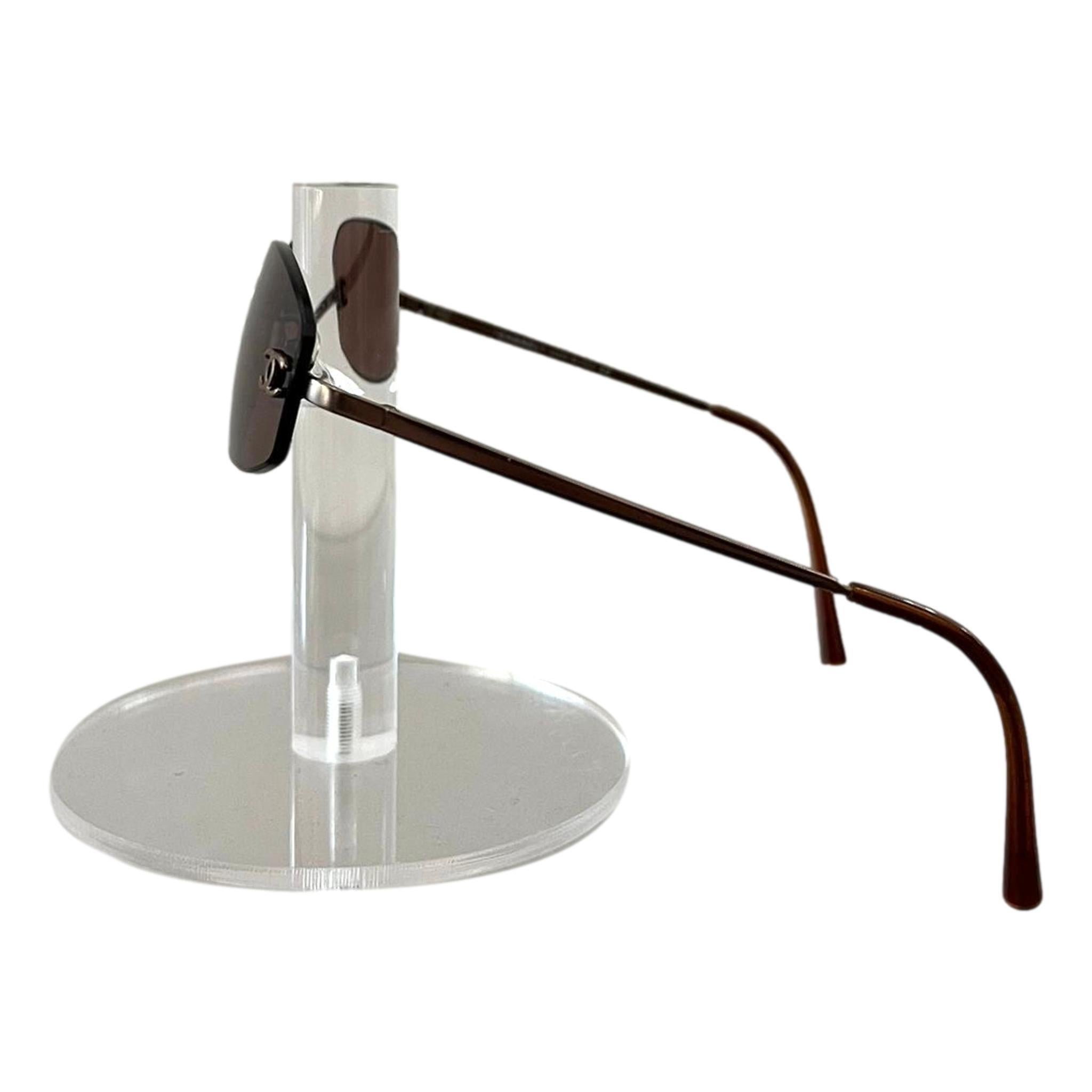 Chanel Rimless 'CC' Logo Sunglasses

Bronze, oval shaped sunglasses with 'CC' logo to the side of the lens and 'Chanel' engravement to the bridge.

Featuring thin brown, metal arms with gold 'CC' logo engraved detail.

Size – One Size

Condition –