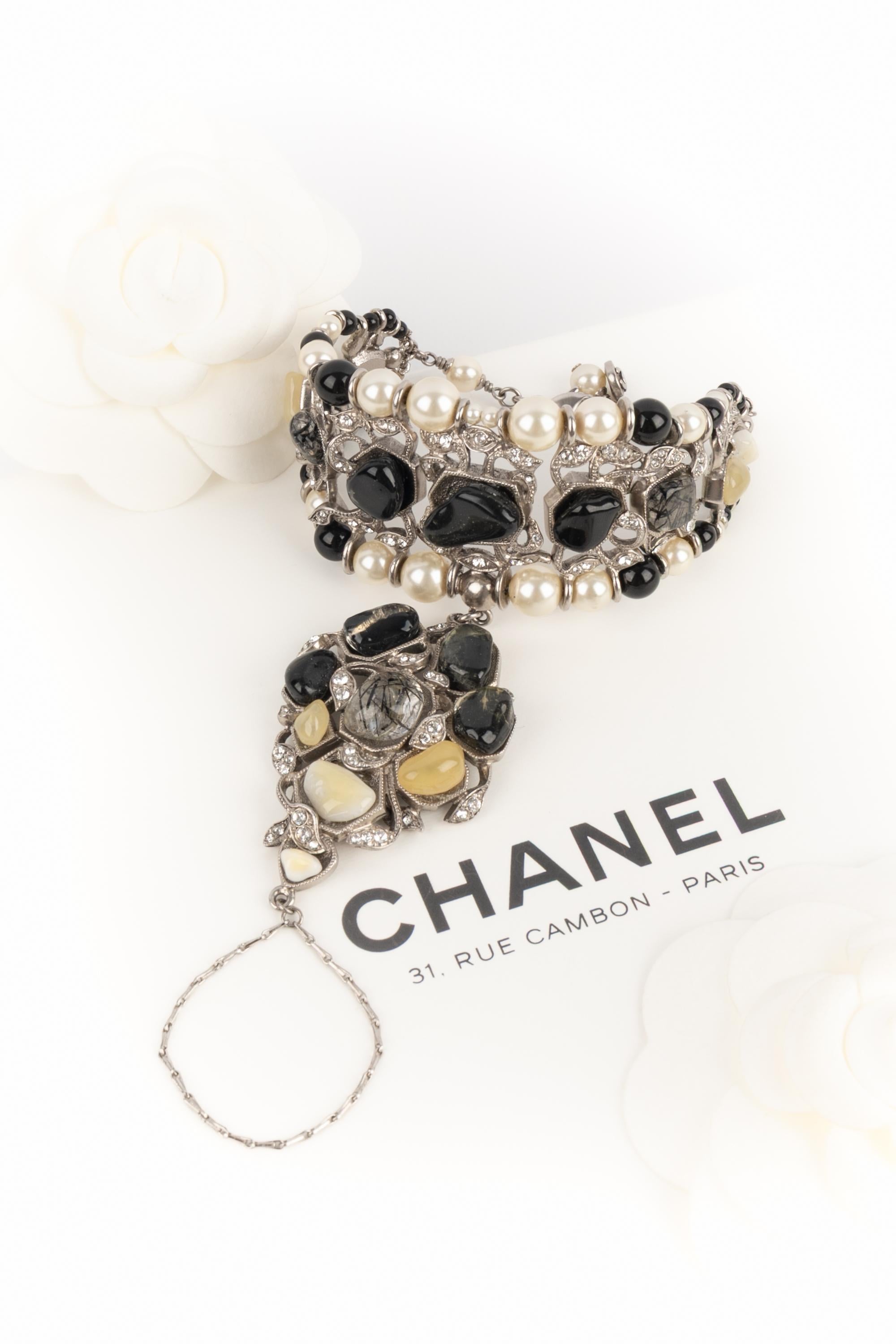CHANEL - (Fabriqué en France) Bracelet anneau en métal argenté avec perles fantaisie, perles de verre noir et cabochons en pâte de verre baroque. Collection Pre-Fall 2012.

Condit :
Très bon état.

Dimensions :
Longueur : de 16 cm à 19 cm

SKU:BRAB3