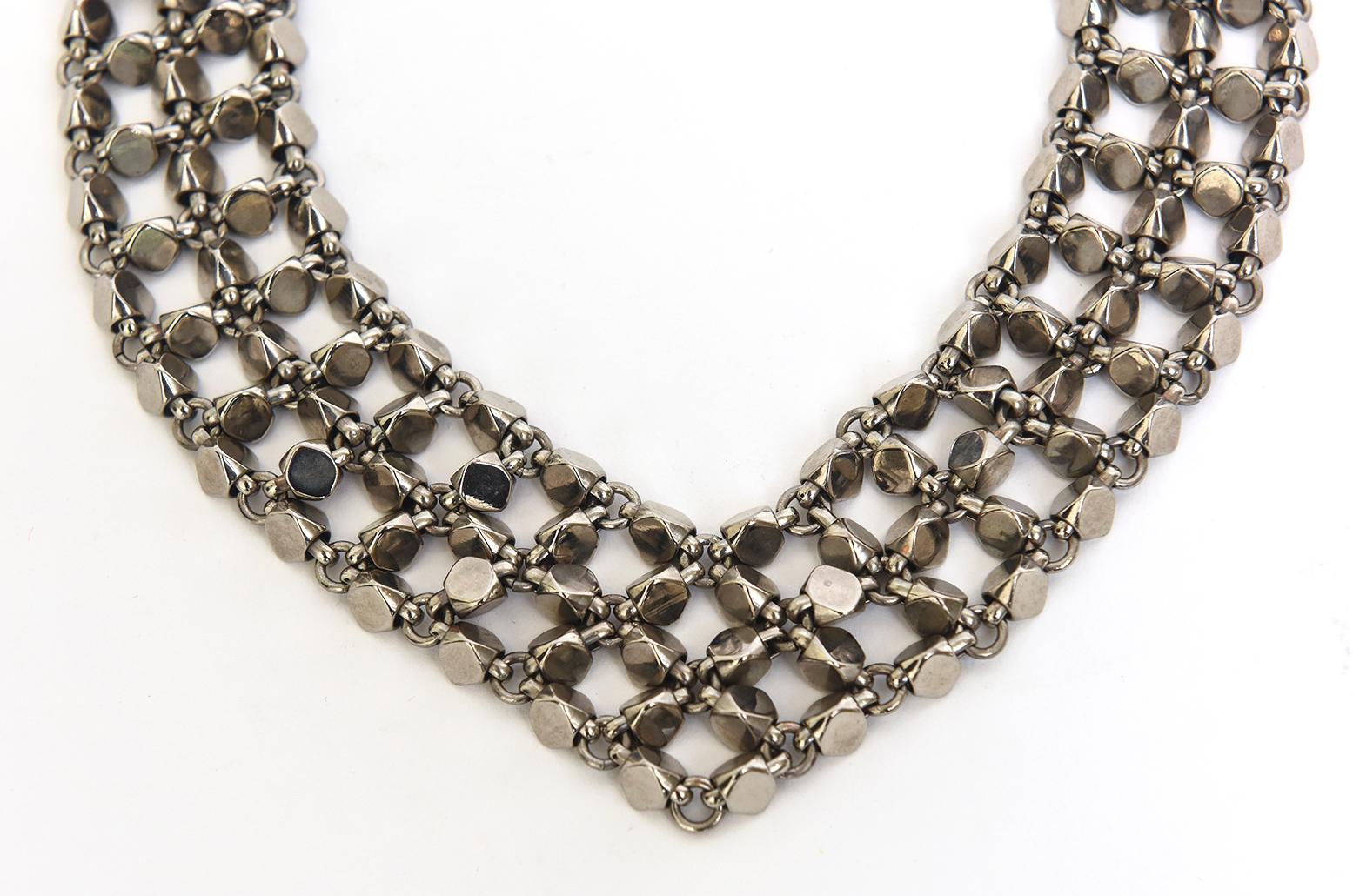  This hot fabulous rock stud Chanel signed necklace is in the shape of a V on your neck. It is signed Made in France Chanel '98. It is silver toned metal and each side has 3 rows of studs that are connected. There are many cc's on the final back