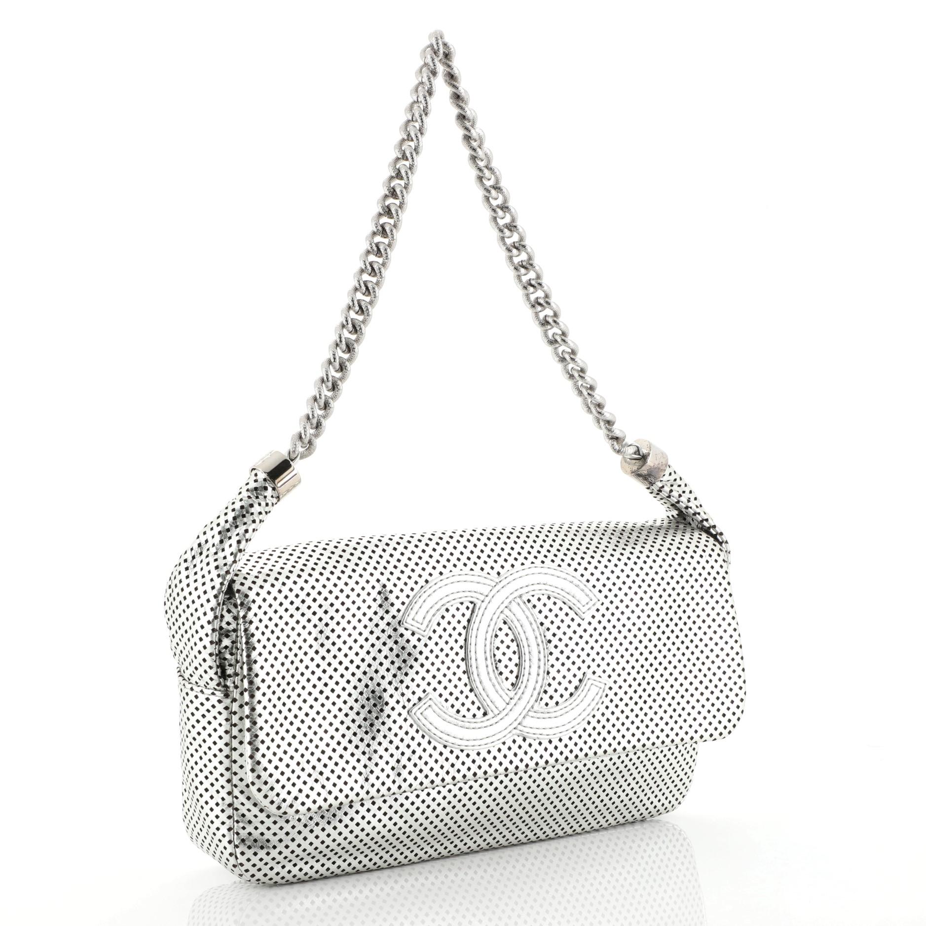 This Chanel Rodeo Drive Flap Bag Perforated Leather Medium, crafted in silver perforated leather, features chain link shoulder strap, CC stitched logo on front flap, protective base studs, and silver-tone hardware. Its magnetic snap button closure