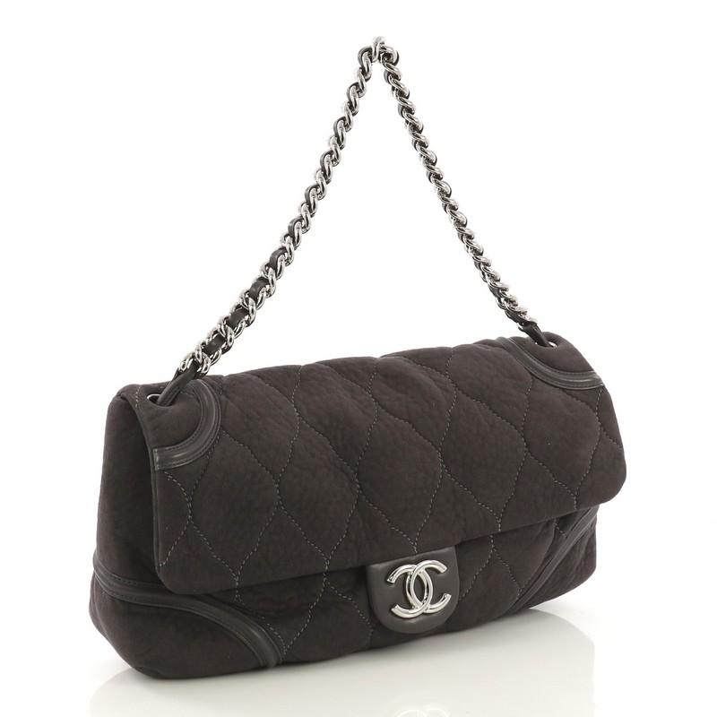 This Chanel Rodeo Drive Flap Bag Quilted Microsuede Large, crafted in grey quilted microsuede, features woven-in leather chain strap, leather trim and silver-tone hardware. Its magnetic snap button closure opens to a silver fabric interior with zip