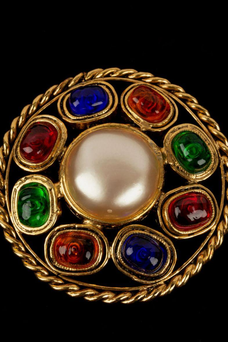 Chanel -(Made in France) Round brooch in gilded metal, paved with glass paste cabochons and centered with a pearly cabochon. Collection 2cc3.

Additional information:
Dimensions: Diameter: 5 cm
Condition: Very good condition
Seller Ref number: BRB83