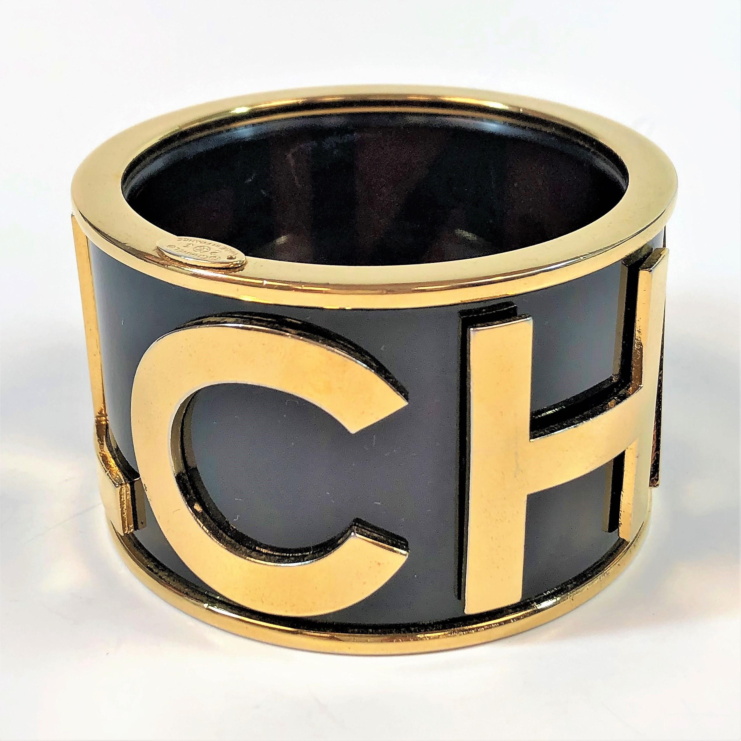 Runway 1986 Season 23 previewed this large size (just under 2 inches wide) 
Cuff/Bangle. The black background is accented with 1  1/2 inch high
gold tone capital letters spelling out the word C H A N E L. The top and bottom 
are capped with the same