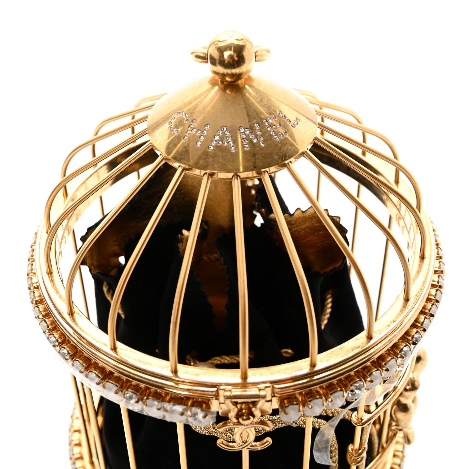This stunning piece is made of metal in the shape of a bird cage, with blue agate stones and cc's adorning the bottom of the cage with 2 birds sitting on the front of the cage. Limited edition piece. Designer Virginie Viard.

Color: gold