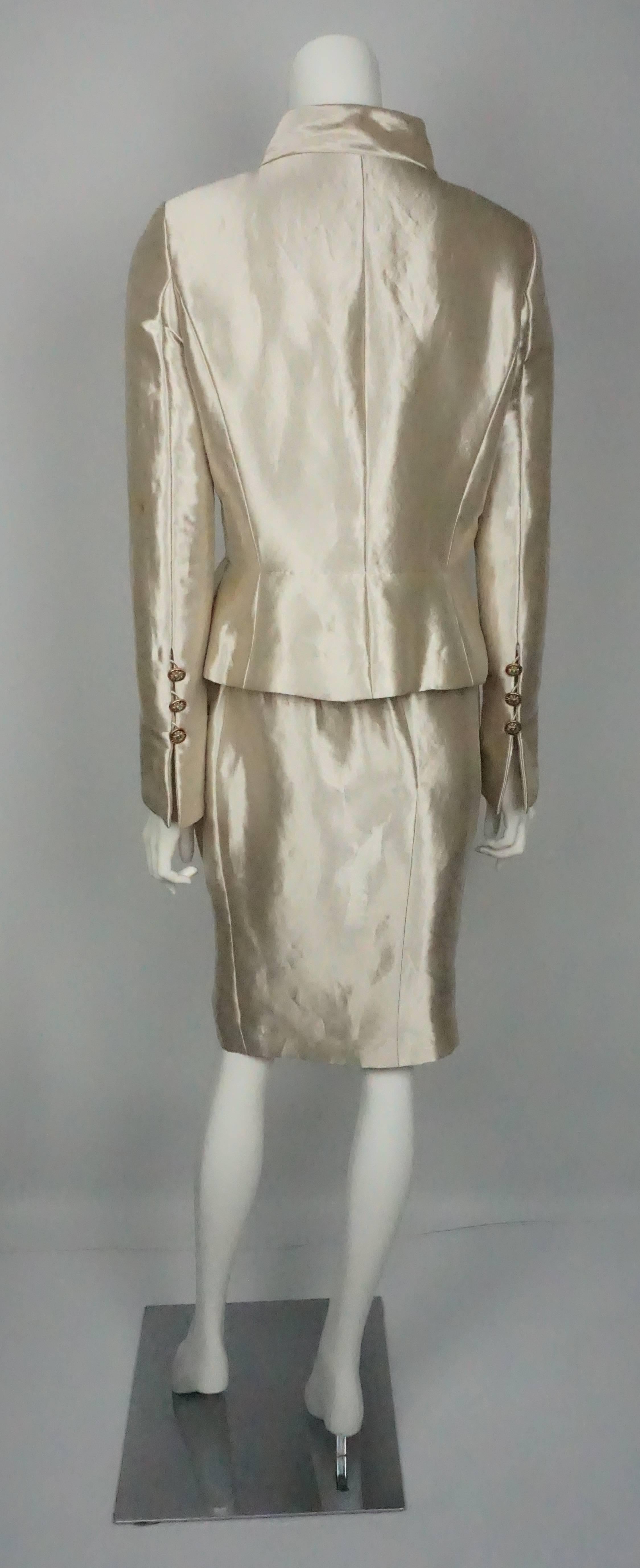 Traje de falda Chanel de seda metalizada dorada con botones Gripoix - 40  Esta pieza de pasarela fue el look 45 del desfile Chanel Pre-Fall 2012. Esta creación de Karl Lagerfeld es una obra de arte. La chaqueta de seda Lame tiene 6 espectaculares