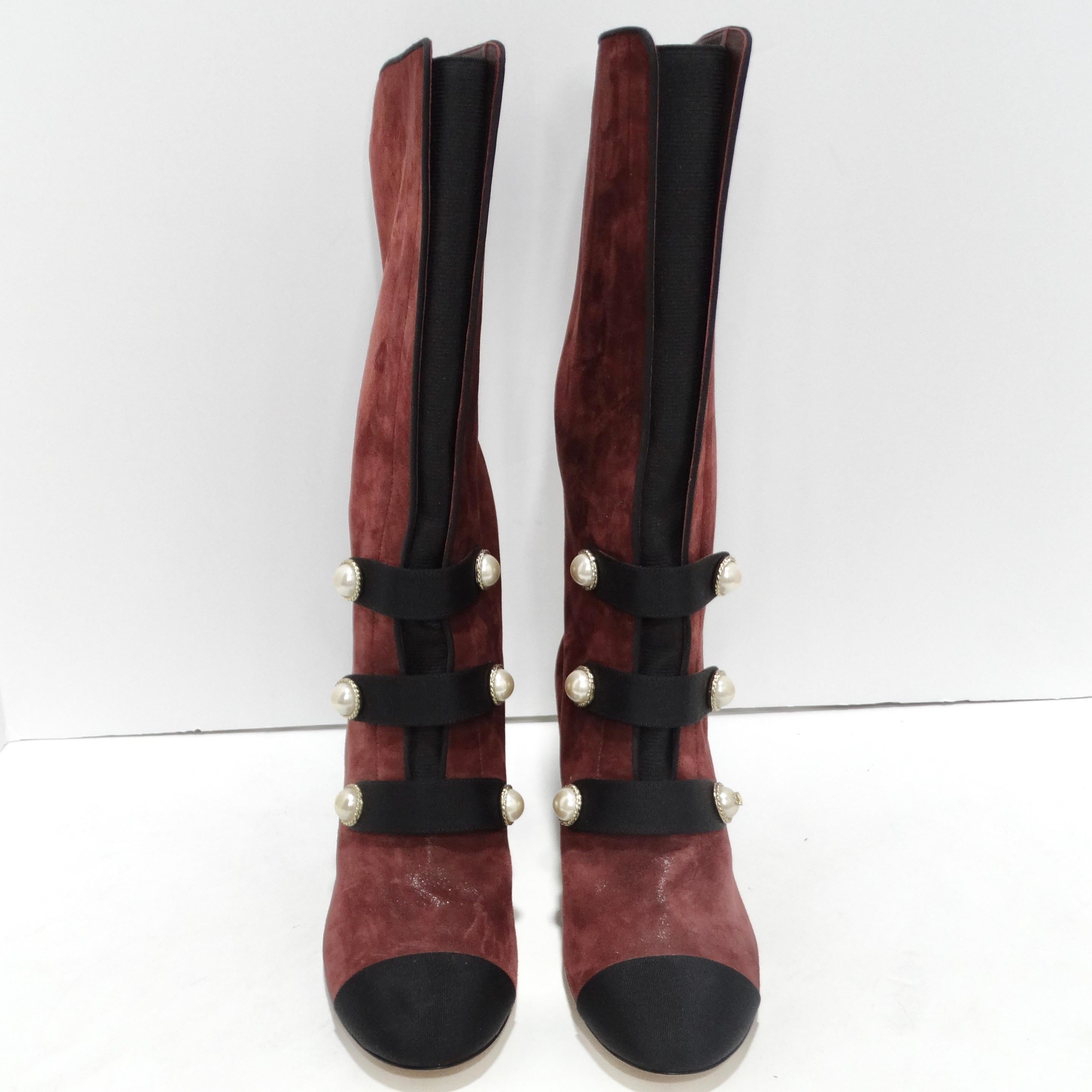 Step into timeless elegance with the Chanel Russian Collection Bordeaux Boots. These burgundy red block heel boots exude sophistication, featuring black toe caps and a faux pearl button adorned with black straps across the front. A signature Chanel